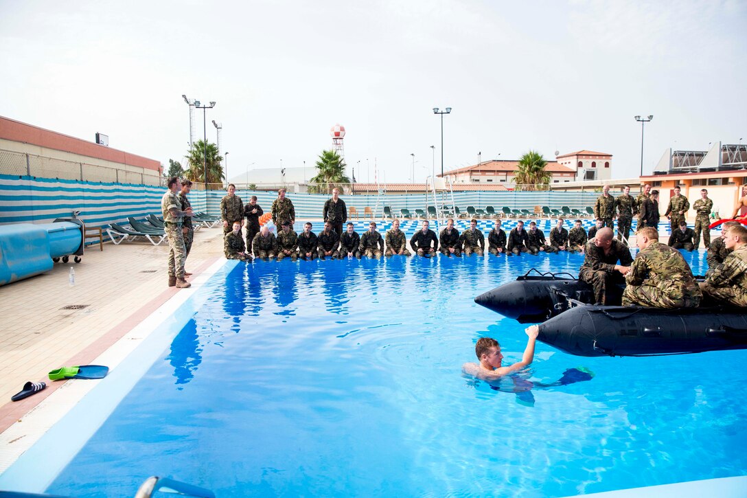 U.S. Marines and British Royal Marines with Special-Purpose Marine Air-Ground Task Force Africa 14 demonstrate proper procedures in a zodiac combat reconnaissance rubber craft while commands are given during a small-craft capsize exercise aboard Naval Air Station Sigonella, Italy, Aug. 20, 2014. Service members watched the proceedings and then performed the tasks. They will be performing and sharing the same techniques for an upcoming Theater Security Cooperation engagement, when they work alongside partner nations in Africa. (U.S. Marine Corps photo by Cpl. Shawn Valosin)