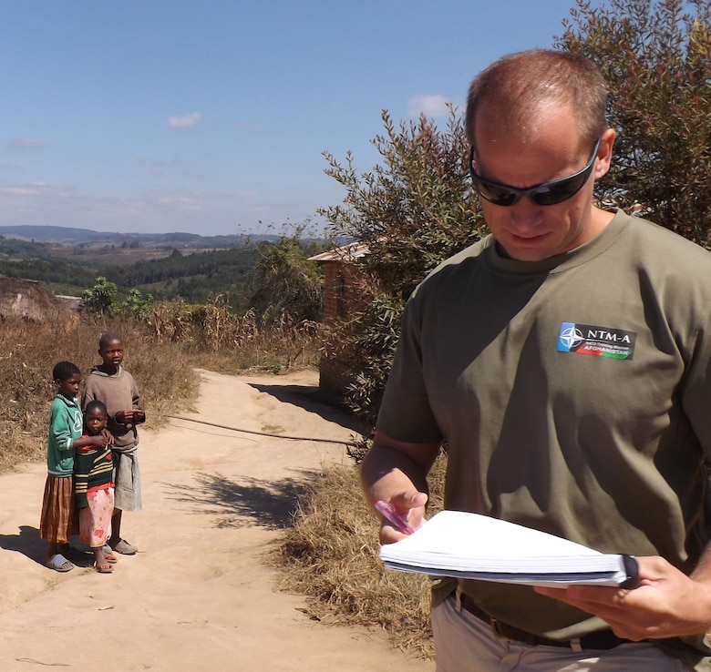 Robert Lawrence, civil engineer Philadelphia District USACE compiles his notes during an assessment of the roads in Tanzania while local children look on.