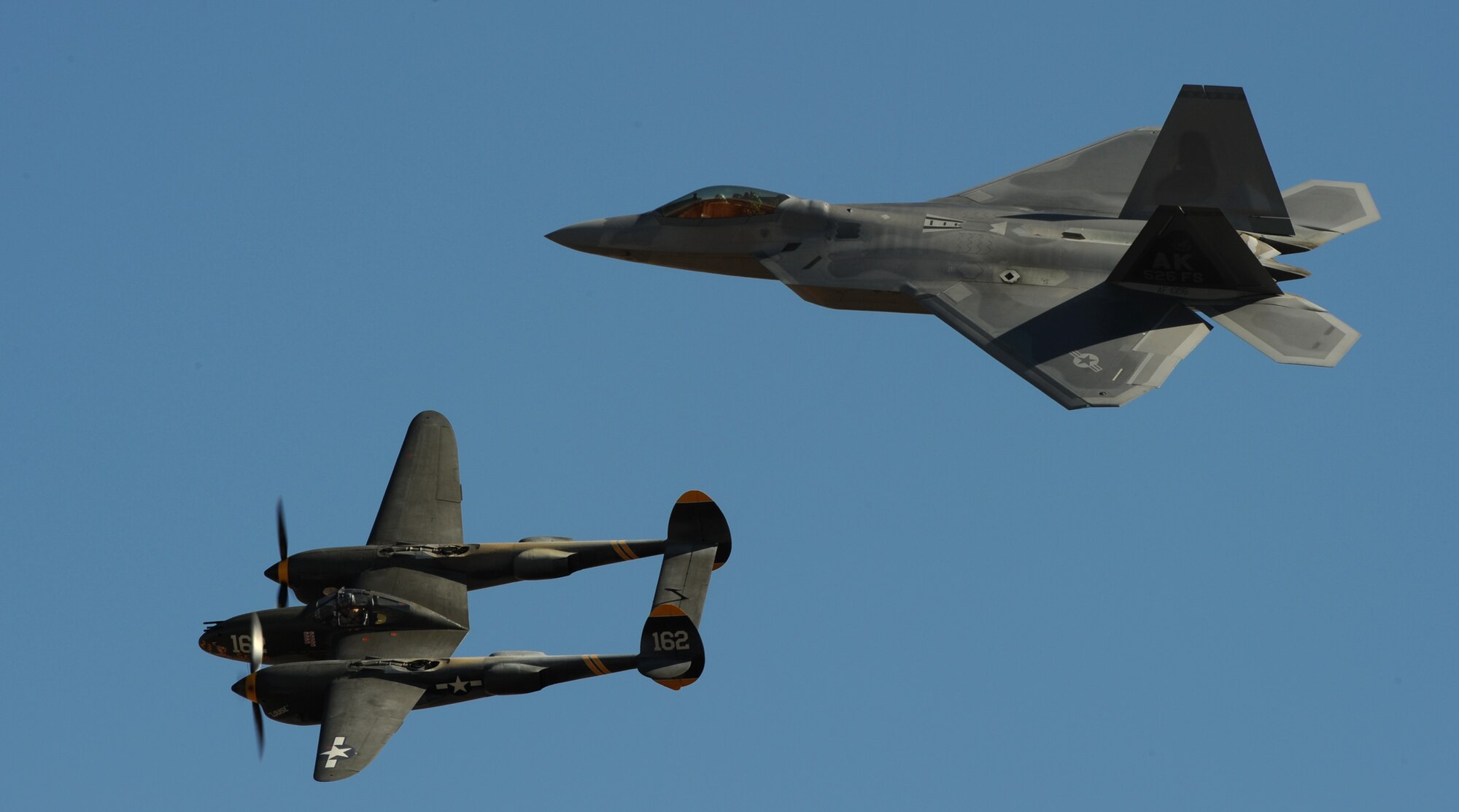 A United States Air Force F-22 Raptor and a vintage P-38 Lighting perform a Heritage flight during the California Capital Airshow in Sacramento, Calif., Sept. 6, 2014. The Heritage Flight Program represents the evolution of the Air Force airpower by flying today’s state-of-the-art fighter aircraft in close formation with historic fighter aircraft. (U.S. Air Force photo by Staff Sgt. Robert M. Trujillo/Released) 