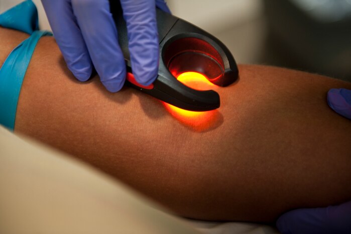 Senior Airman Erica Degrate, 99th Medical Surgical Operations Squadron computer tomography technologist, uses a transillumination device on Airman 1st Class David Mathews, 99th MSGS phase two diagnostic imaging technologist student, at the Mike O’Callaghan Federal Medical Center, Nellis Air Force Base, Nev., Aug. 26, 2014. A transillumination device is used to help identify and locate a patient’s veins that may be hard to find by hand. (U.S. Air Force photo by Airman 1st Class Thomas Spangler)