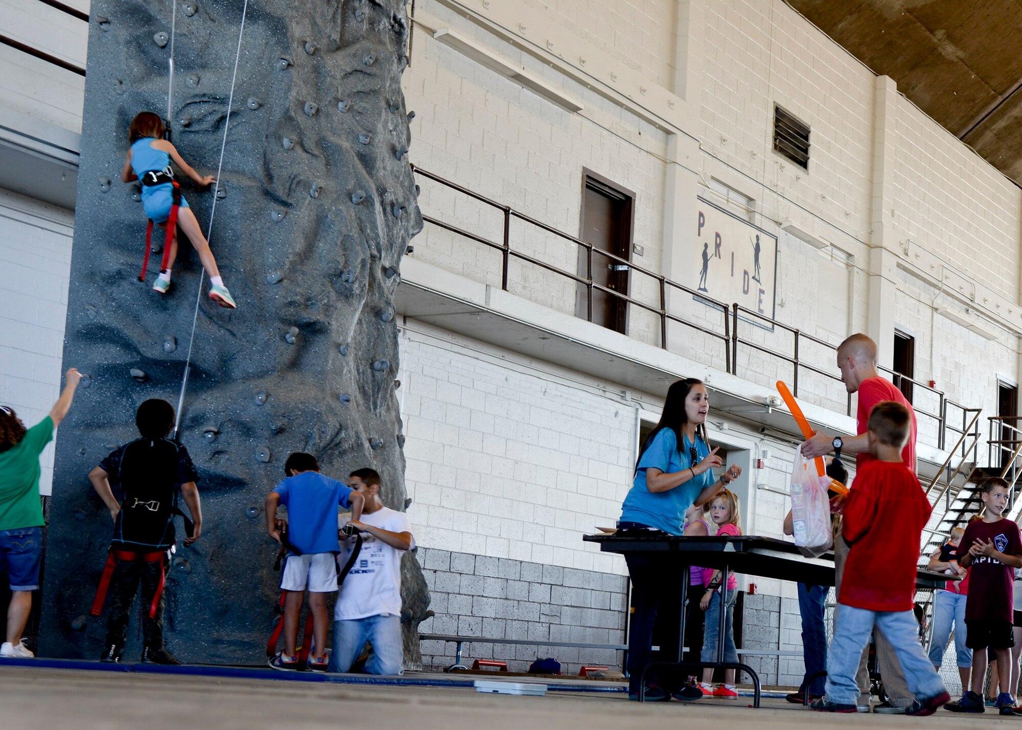 Children climb a rock wall during a Back to School Round-Up event inside the Pride Hangar at Ellsworth Air Force Base, S.D., Sept. 6, 2014. The event included games and activities for families in celebration of the start of 2014 – 2015 school year. (U.S. Air Force photo by Senior Airman Anania Tekurio/Released)