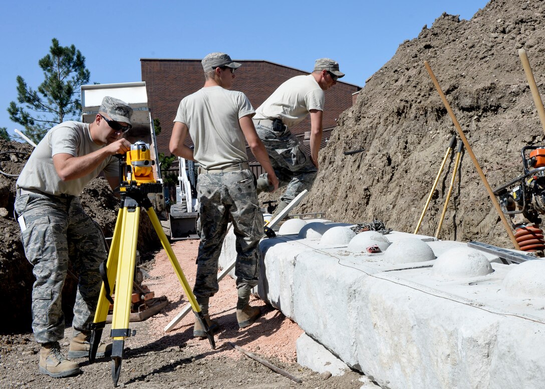 Tech. Sgt. James Banik, 28th Civil Engineer Squadron heavy equipment technician, adjusts a laser leveler during construction of a retaining wall outside the 28th Bomb Wing Headquarters building at Ellsworth Air Force Base, S.D., Sept. 8, 2014. The wall was built to protect the building from water leaking in during heavy downpours. (U.S. Air Force photo by Senior Airman Anania Tekurio/Released)
