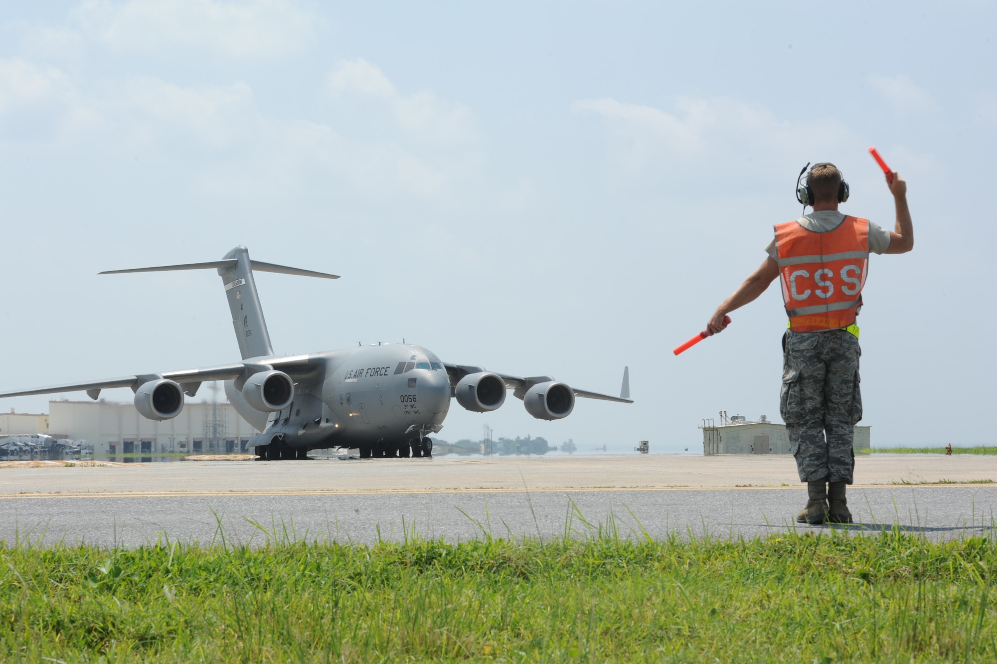 U.S. Air Force Staff Sgt. Nicholas Otos, 733rd Air Mobility Squadron avionics technician craftsman, marshals a C-17 Globemaster III into its spot on the flight line for inspection and servicing on Kadena Air Base, Japan, Sept. 9, 2014. The 733rd AMS aircraft maintenance unit maintains multiple airframes on Kadena to ensure aircraft are mission ready at all times. (U.S. Air Force photo by Airman 1st Class Zackary A. Henry)