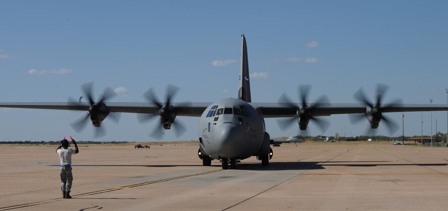 A U.S. Air Force Airman signals a C-130J Super Hercules as it taxis on the runway Sept. 9 2014, at Dyess Air Force Base, Texas. Members of the 317th Airlift Group, returned from a deployment to U.S. European Command in support of U.S. Africa Command operation. (U.S. Air Force photo by Airman 1st Class Alexander Guerrero/Released)