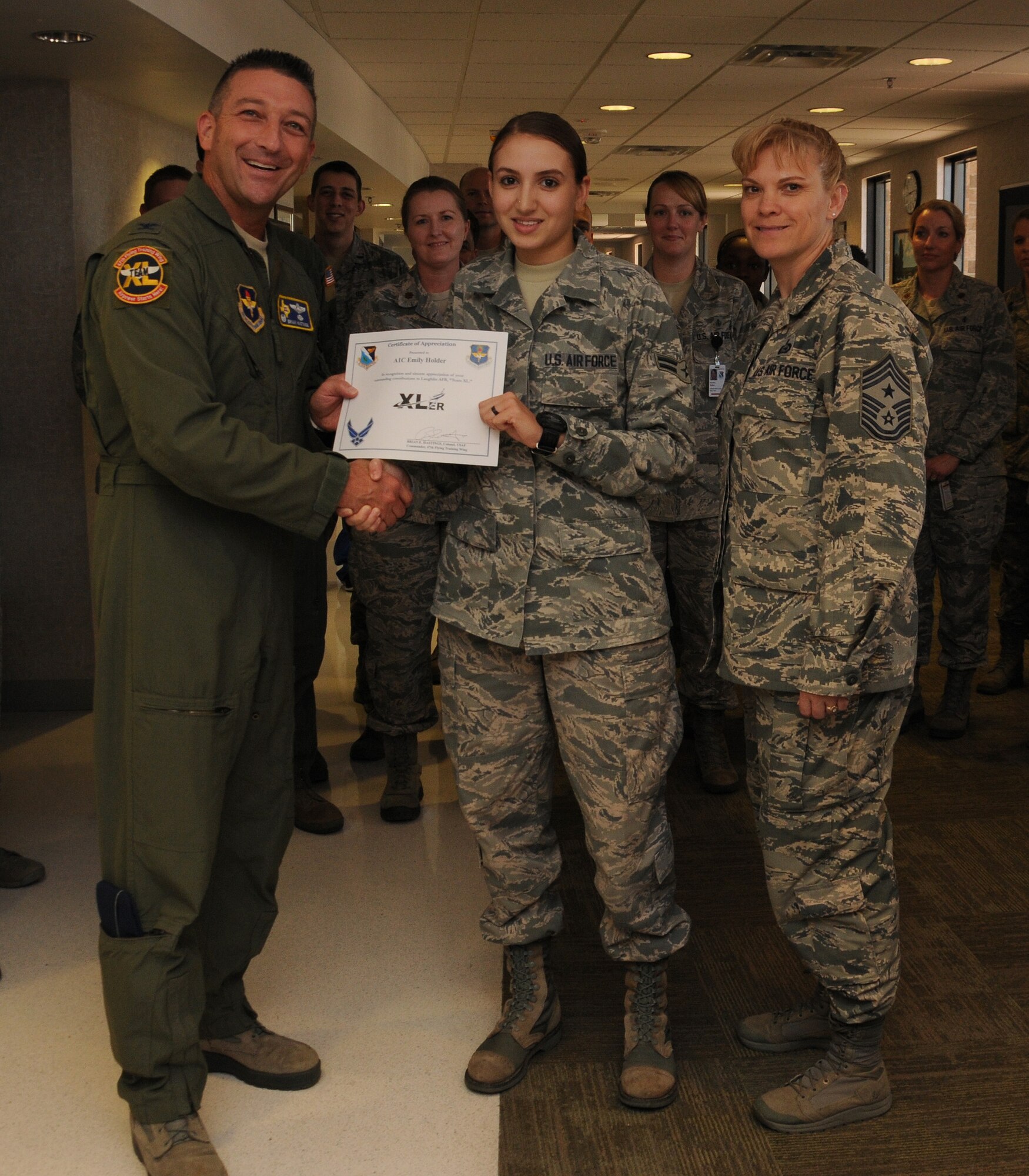 Airman 1st Class Emily Holder, center, 47th Medical Operations Squadron aerospace medical technician, poses with Col. Brian Hastings, left, 47th Flying Training Wing commander, and Chief Master Sgt. Teresa Clapper, right, 47th FTW command chief, after being presented the XLer of the week award here Sept. 10, 2014. The XLer is a weekly award chosen by wing leadership and given to those who consistently make outstanding contributions to their unit and Laughlin. (U.S. Air Force photo by Airman 1st Class Ariel D. Delgado)(Released)