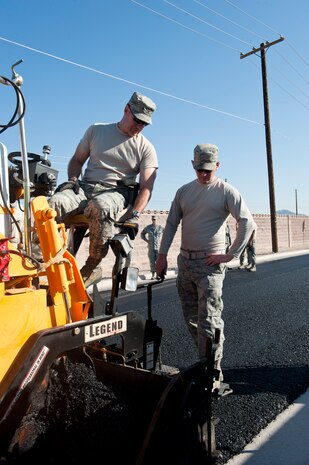 Senior Airman Brian Durkin (right), 99th Civil Engineering Squadron heavy equipment operator, observes Col. Richard Boutwell, 99th Air Base Wing commander, operate an asphalt-paving machine along Ellsworth Ave., at Nellis Air Force Base, Nev., Sept. 10, 2014. The 99th CES has used 1,340 tons of asphalt to repave roughly 2,000 feet of Ellsworth Ave. The repaving has been going on for two-and-a-half weeks and is scheduled to be completed Sept. 26. (U.S. Air Force photo by Airman 1st Class Thomas Spangler)