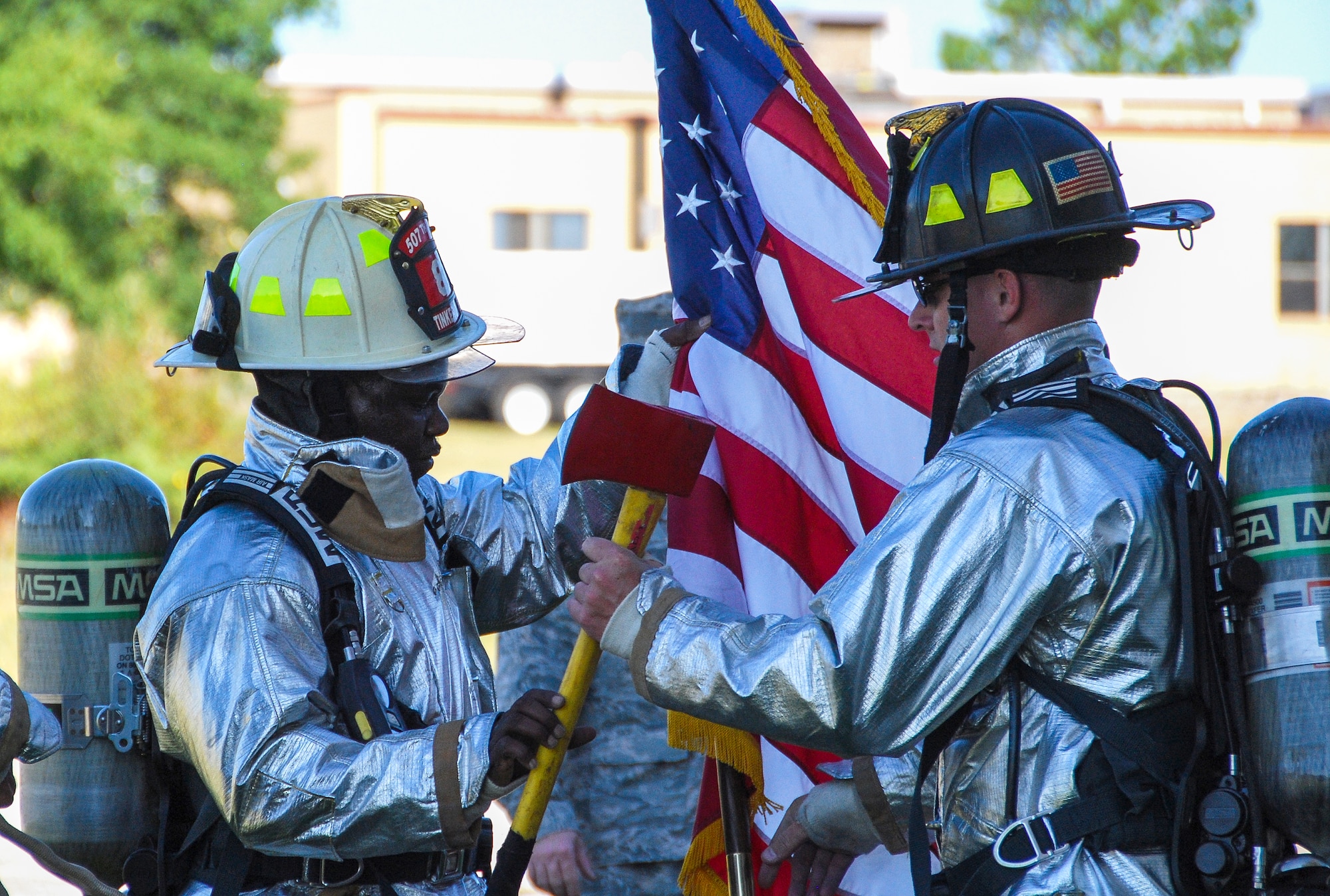 Firefighters from the 507th Civil Engineer Squadron trade the U.S. flag and an axe during the 5th annual fire climb Sept. 7 at the fire training tower here.  The axe and flag were pieces of several packs carried up and down the tower stairs as members of the CES and the wing climbed the equivalent of 110 stories to commemorate the 343 firefighters, emergency medical technicians and paramedics who lost their lives during the 9/11 attacks on the World Trade Centers. (U.S. Air Force photo/Senior Airman Krystin Trosper)