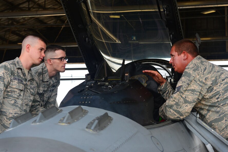 [From left] U.S. Air Force Airman 1st Class Kory Gustafson, 7th Intelligence Squadron Detachment 2 intelligence specialist, and Senior Airman Jim McGeehin, 7th IS Det 2 language analyst, both assigned to Fort Gordon, G.A., listen to Tech. Sgt. Mitchell Floyd, 20th Aircraft Maintenance Squadron integrated avionic systems mechanic, explain the inner workings of the cockpit of an F-16CM Fighting Falcon at Shaw Air Force Base, S.C., Sept. 10, 2014. While touring the flightline, 16 Airmen stationed at Ft. Gordon learned about the F-16 and its various capabilities. (U.S. Air Force photo by Airman 1st Class Jensen Stidham/Released)