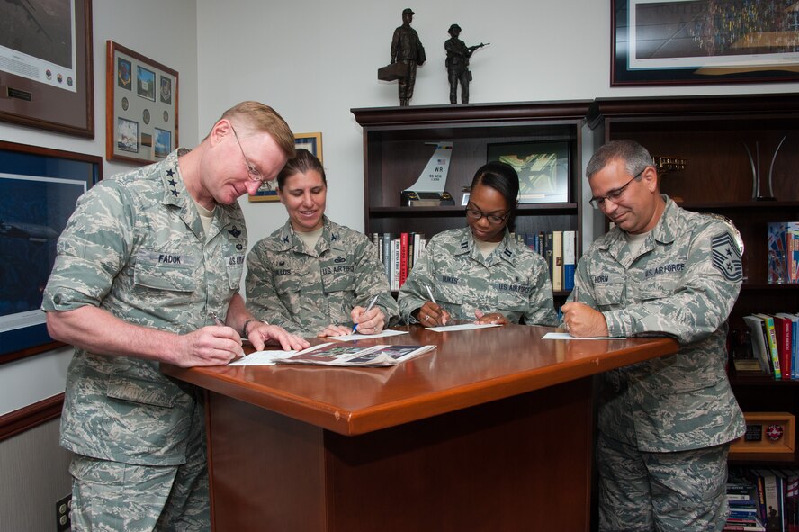 Lieutenant General David Fadok, Commander and President of Air University, Colonel Andrea Tullos, Commander, 42nd Air Base Wing, Captain Juanita Dukes, Maxwell AFB Combined Federal Campaign project manager, and Chief Master Sergeant Timothy Horn, Command Chief Master Sergeant, AU, sign their 2014 CFC pledges in the traditional paper and ink form, Sep. 8.  (US Air Force photo by Melanie Rodgers Cox)
