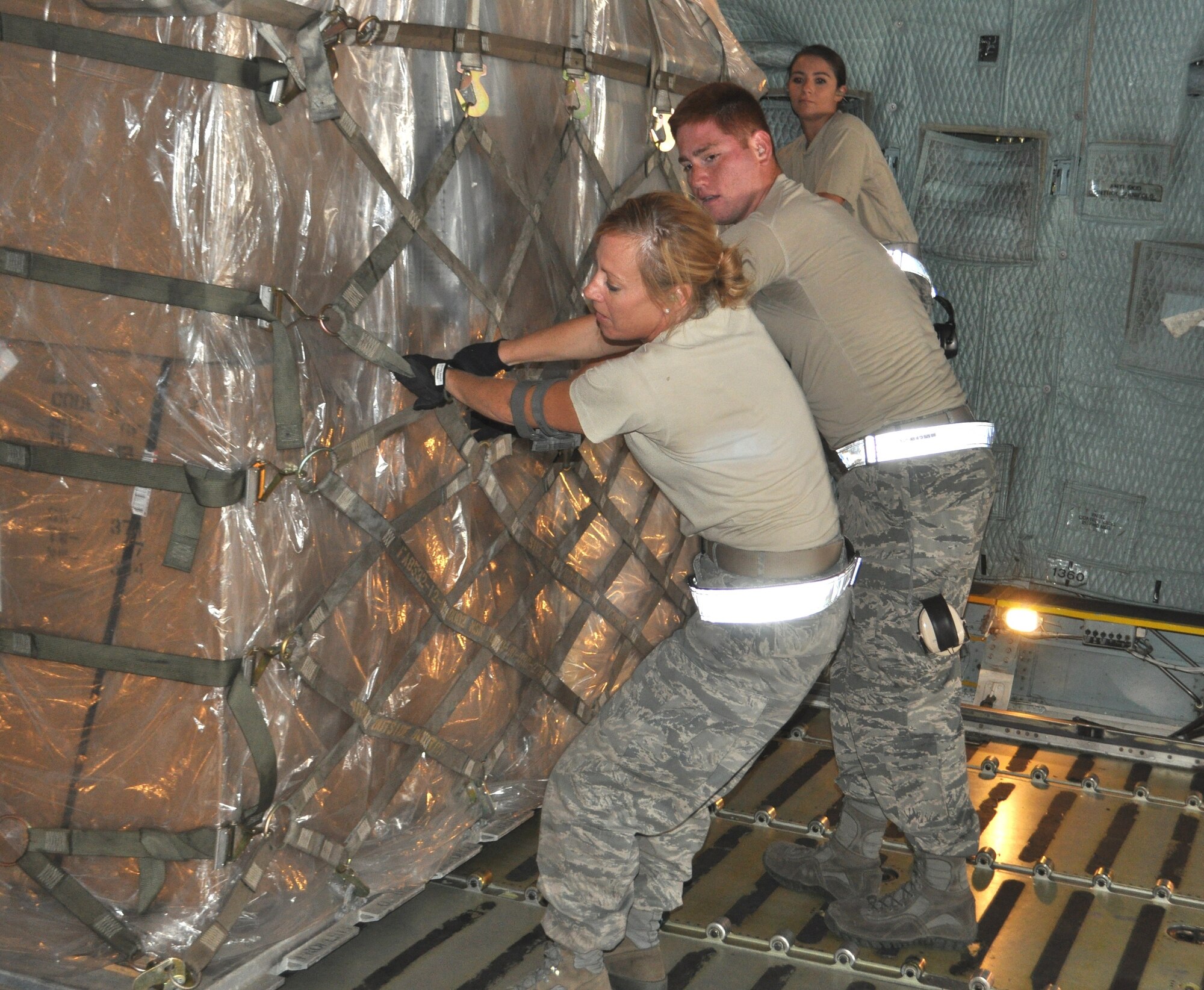 TRAVIS AIR FORCE BASE, Calif. -- Left to right: Senior Airmen Michelle Grazier and Matthew Hammond, and Airman 1st Class Jessica Cummings rock and roll a pallet to get it straightened, and rolling smoothly toward the front of a C-5 during a full 36-pallet load. All three are reservists who worked and trained alongside the 60th Aerial Port Squadron in August. Grazier and Hammond are assigned under the 433rd Airlift Wing, to the 26th APS, at Joint Base San Antonio, and Cummings is with the 82nd APS here. (U.S. Air Force photo/Ellen Hatfield)