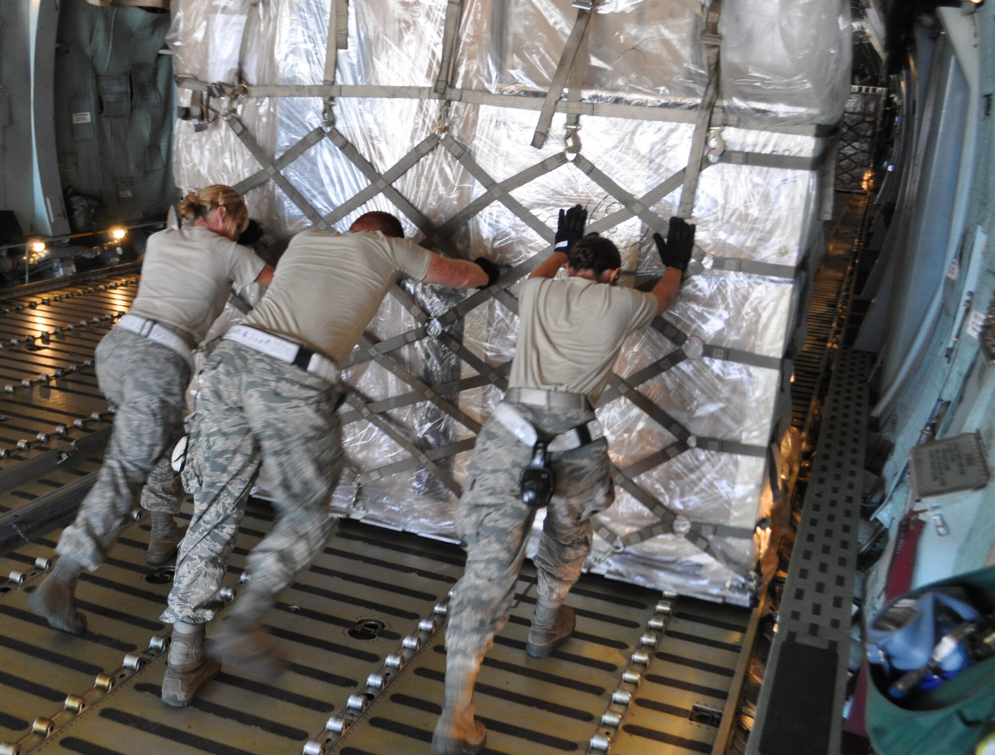 TRAVIS AIR FORCE BASE, Calif. -- Team Travis and Joint Base San Antonio aerial porters got the opportunity to complete a full, 36-pallet load of a C-5 Galaxy Aug. 18, 2014, during proficiency training. Here, from the left, Senior Airmen Michelle Grazier and Matthew Hammond, and Airman 1st Class Jessica Cummings, roll a full pallet onto the aircraft. Grazier and Hammond are with the Reserve’s 26th Aerial Port Squadron, JB San Antonio, and Cummings is assigned to the 82nd APS, under the 349th Air Mobility Wing here. The Texas reservists were able to complete their two weeks’ annual tour under the tutelage of the 60th APS, and experience the associate partnership between the active and reserve wings. (U.S. Air Force photo/Ellen Hatfield)