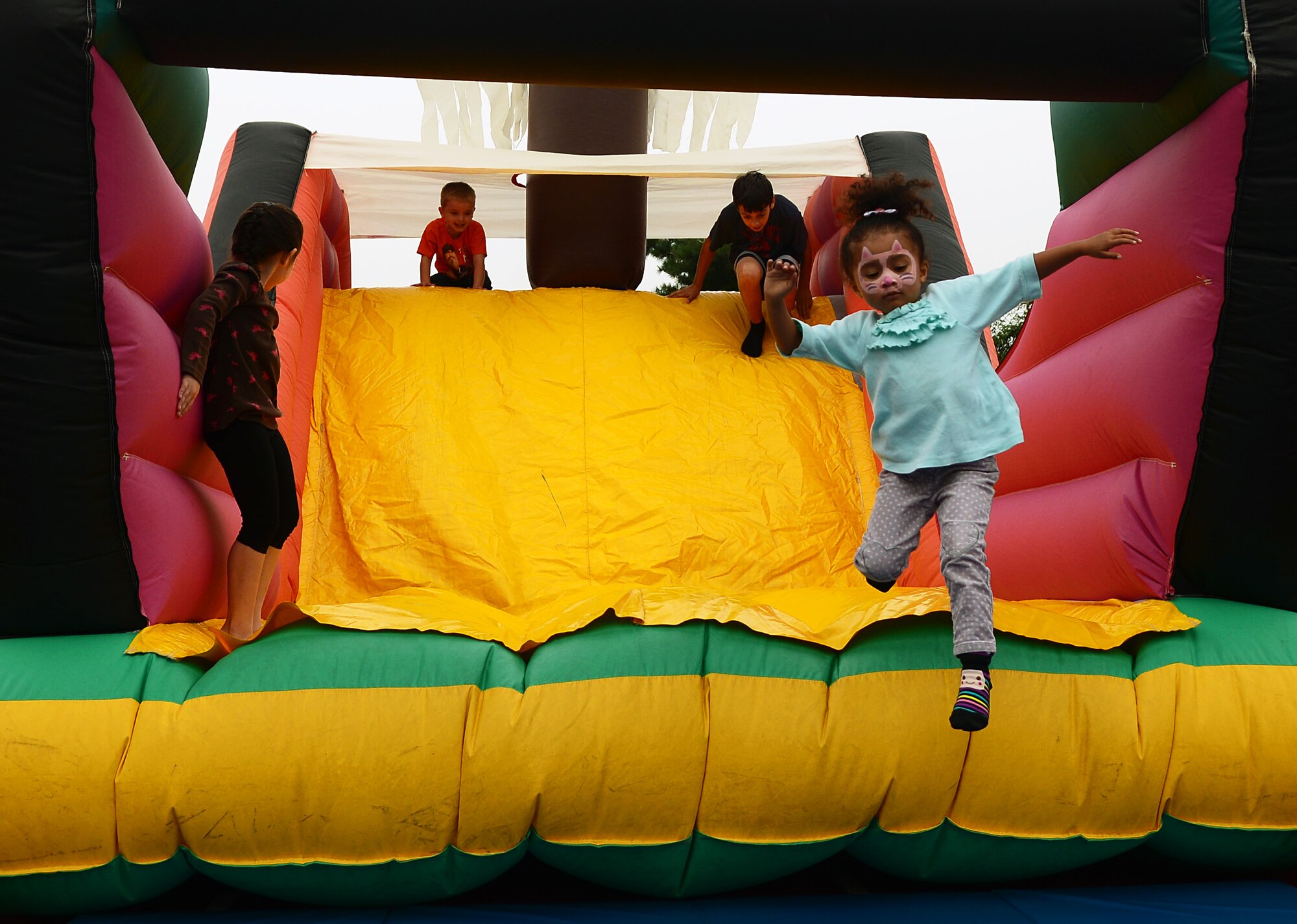 Team Mildenhall and Liberty Wing children play on a slide during the 100th Force Support Squadron Youth Center Day for Kids Sept. 6, 2014, at RAF Mildenhall, England. Day for Kids is an annual event filled with games, food and fun. (U.S. Air Force photo/Airman 1st Class Jonathan Light/Released)