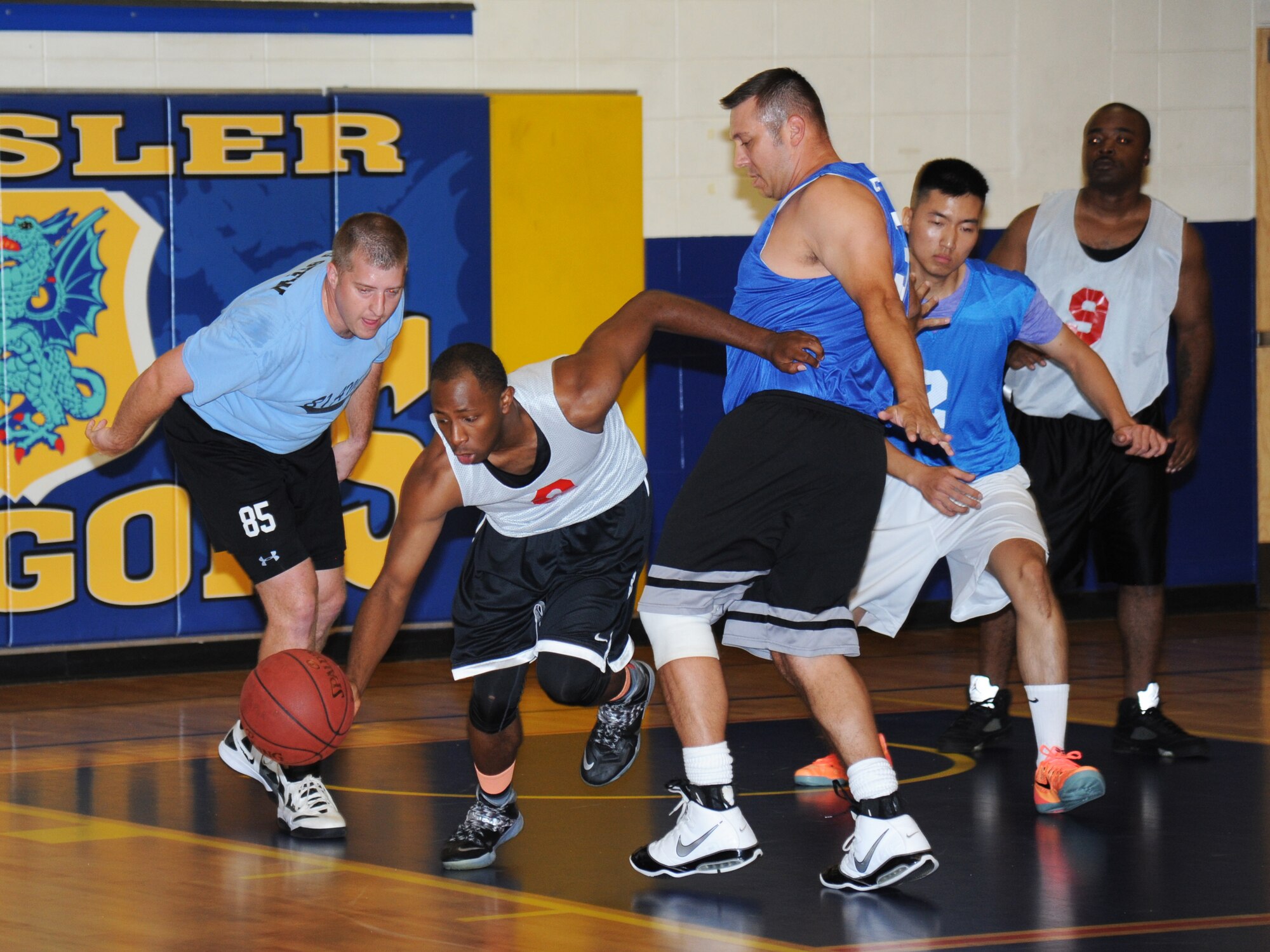 Marcus Toney, Gulfport Army Recruiting Station team, drives the ball through defending players from the 81st Aerospace Medicine Squadron team during an intramural basketball game Sept. 9, 2014, at the Blake Fitness Center, Keesler Air Force Base, Miss.  Following double overtime, the Gulfport Army Recruiting Station team defeated the 81st AMDS team, 74-68. (U.S. Air Force photo by Kemberly Groue)