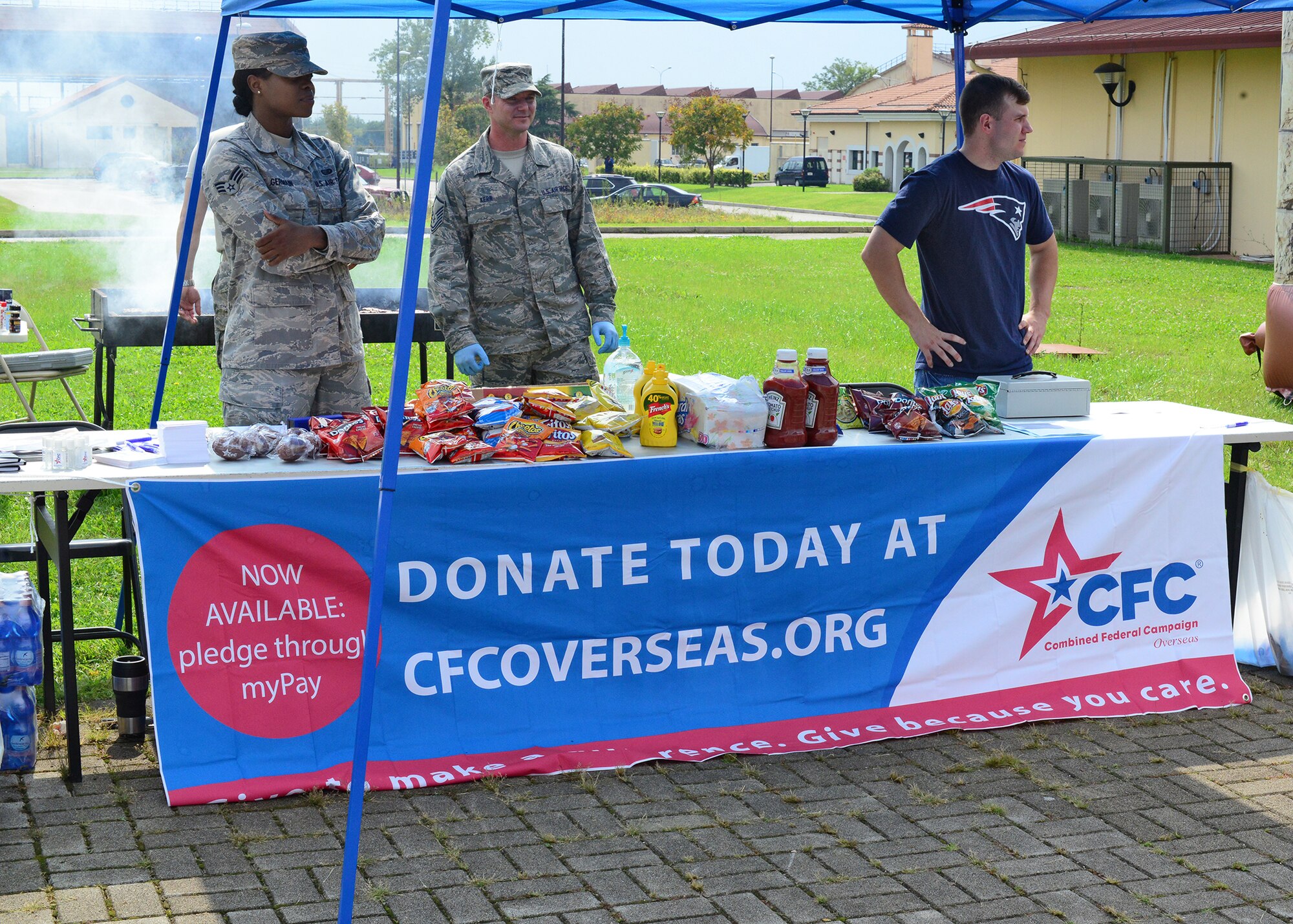 Combined Federal Campaign Overseas volunteers standby to offer food and accept donations for this year’s CFC-O fundraising campaign, Sept. 4, 2014, at Aviano Air Base, Italy. With the help of unit coordinators, the Aviano CFC team has three major events planned, including an exercise-a-thon competition among the squadrons, and a lawn movie night for the grand campaign finale. (U.S. Air Force photo/Staff Sgt. Jessica Hines)
