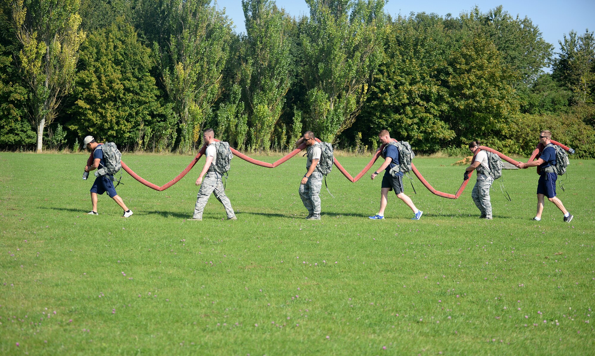 Members of the 100th Security Forces Squadron and 100th Civil Engineer Squadron carry a fire hose during Warrior challenge between Royal Air Forces Lakenheath and Mildenhall security forces and CES firefighters as part of a week-long Battle of the Badges competition on RAF Feltwell, England, Sept. 8, 2014. The athletic competition was a joint effort as part of a Sept. 11 commemoration for first responders. (U.S. Air Force photo by Staff Sgt. Emerson Nuñez/Released)