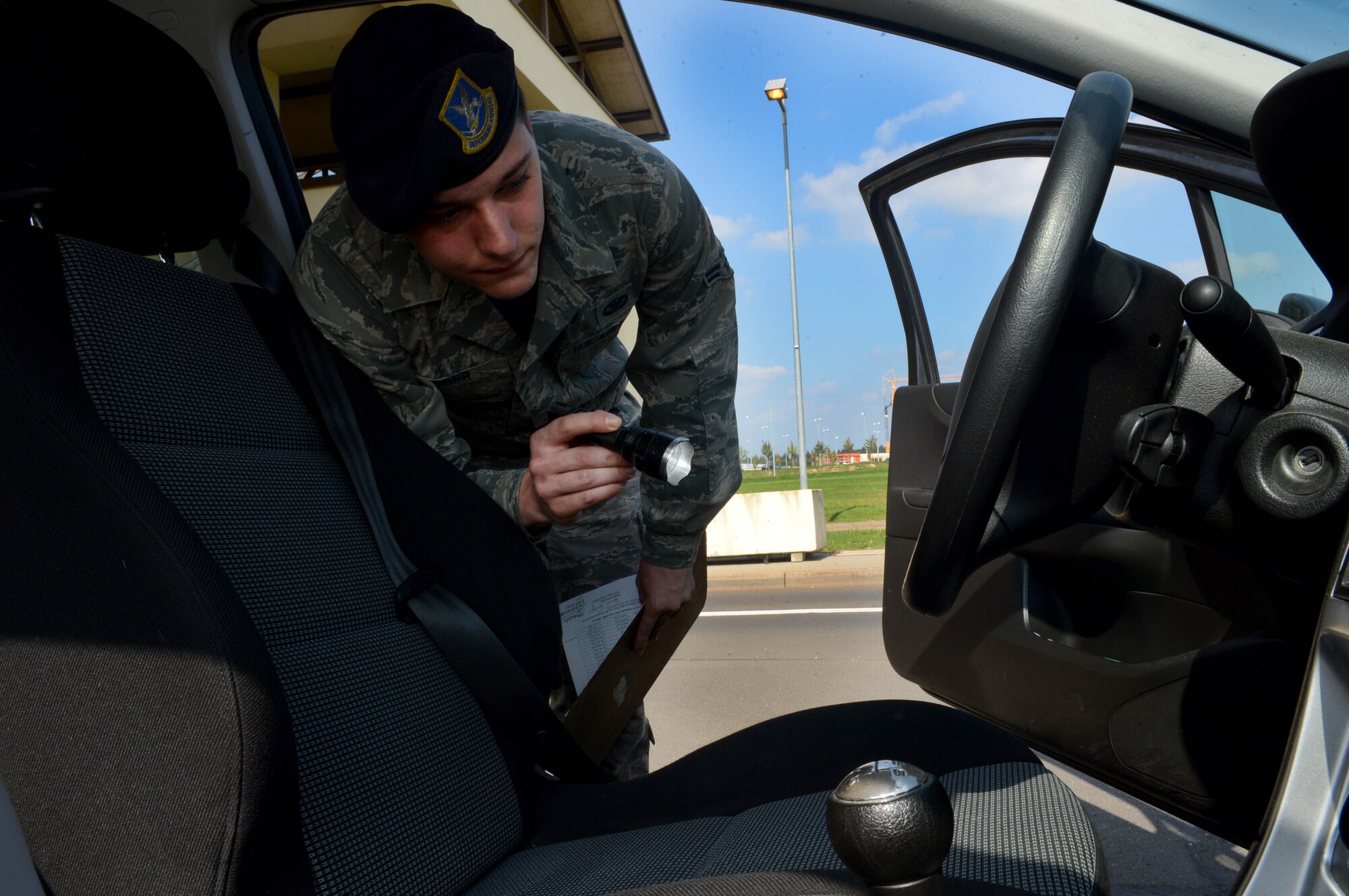 U.S. Air Force Airman 1st Class Justin Barber, 52nd Security Forces Squadron entry controller and native of Jacksonville, Fla., searches the driver side of a vehicle before allowing it entrance to Spangdahlem Air Base, Germany, Sept., 9, 2014. The security forces squadron Airmen perform random vehicle inspections to ensure illegal substances such as explosives, drugs or other weapons are not brought onto the base. (U.S. Air Force photo by Airman 1st Class Kyle Gese/Released)