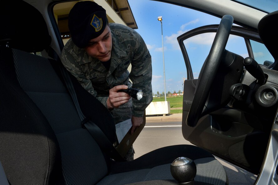 U.S. Air Force Airman 1st Class Justin Barber, 52nd Security Forces Squadron entry controller and native of Jacksonville, Fla., searches the driver side of a vehicle before allowing it entrance to Spangdahlem Air Base, Germany, Sept., 9, 2014. The security forces squadron Airmen perform random vehicle inspections to ensure illegal substances such as explosives, drugs or other weapons are not brought onto the base. (U.S. Air Force photo by Airman 1st Class Kyle Gese/Released)