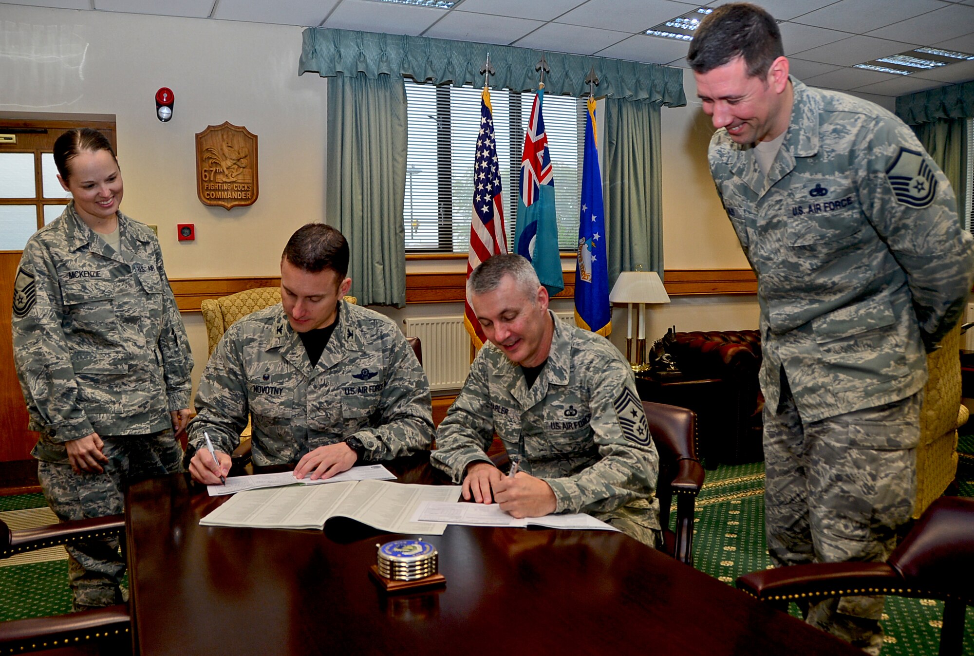 Col. Robert Novotny, 48th Fighter Wing commander, and Chief Master Sgt. Vincent Marler, 48th FW command chief, sign their Combined Federal Campaign pledge cards at Royal Air Force Lakenheath, England, Sept. 5, 2014, with the assistance of Master Sgts. Kelly McKenzie, 48th FW AFSO21 director, and Joseph Miles, 48th Maintenance Squadron section chief of maintenance analysis. The CFC creates a secure way for federal employees to donate to a variety of charities to improve the quality of life for others by providing funds for vital programs. (U.S. Air Force photo by Airman 1st Class Erin O’Shea/Released) 