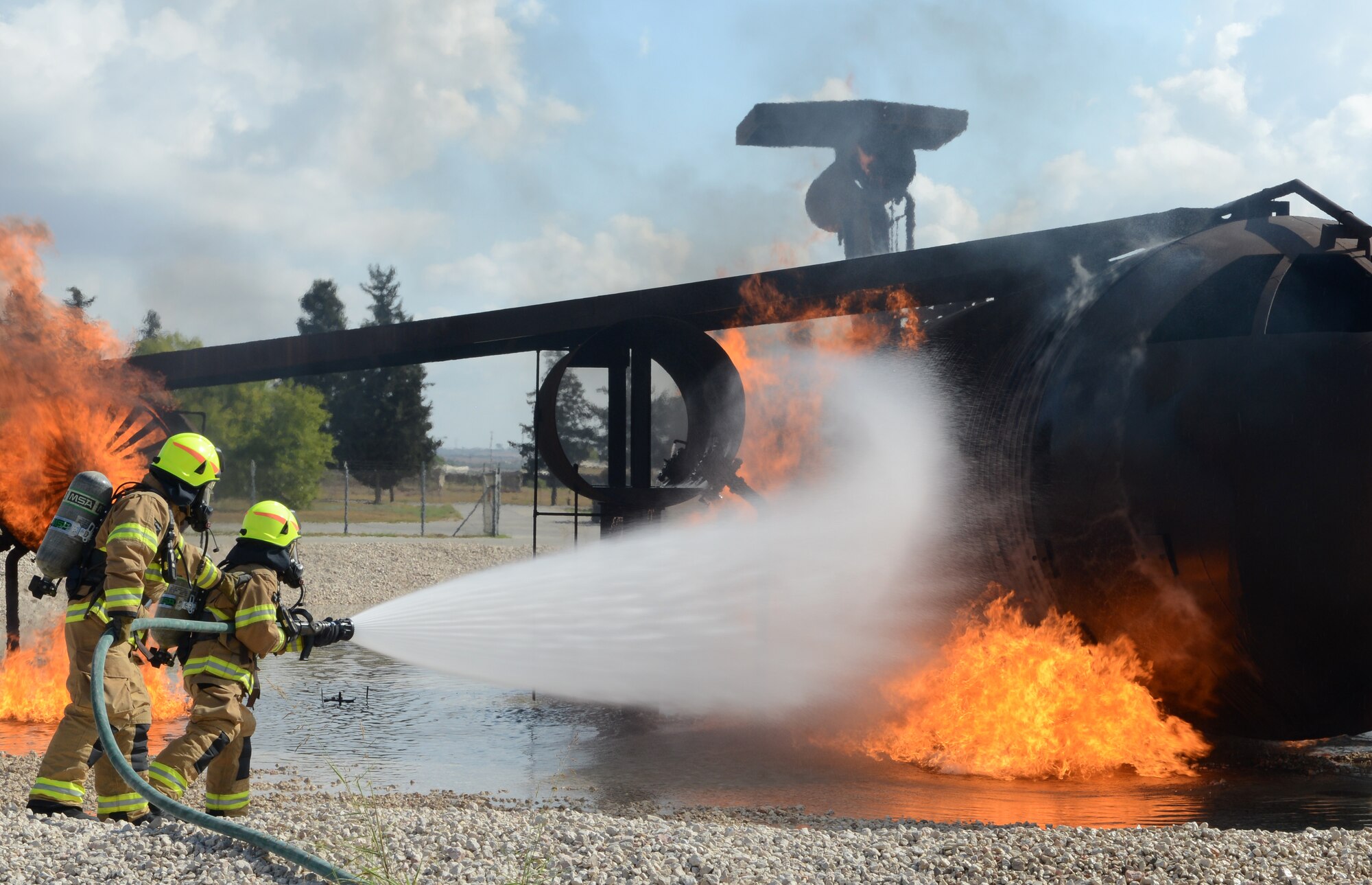 Firefighters from the 39th Civil Engineer Squadron Incirlik Fire Emergency Services, distinguish an aircraft live fire during annual training, Sept. 9, 2014, at Incirlik Air Base, Turkey. Incirlik Fire Emergency service was established to provide structural and crash firefighting, rescue, hazardous materials response, and fire prevention services. (U.S. Air Force photo by Staff Sgt. Caleb Pierce/Released)