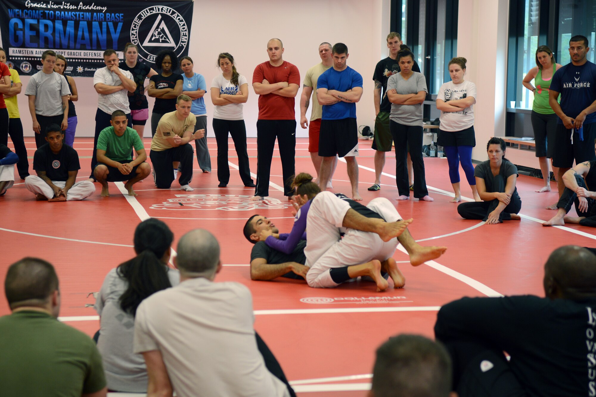 Participants in the Gracie Defense Systems seminar look on as Eve and Rener Gracie, Gracie Defense Systems instructors, demonstrate a self-defense technique at Ramstein Air Base, Germany, Sept. 4, 2014. The seminar was a five-day course, which certified more than 100 instructors to teach self-defense. (U.S. Air Force photo/Senior Airman Timothy Moore)