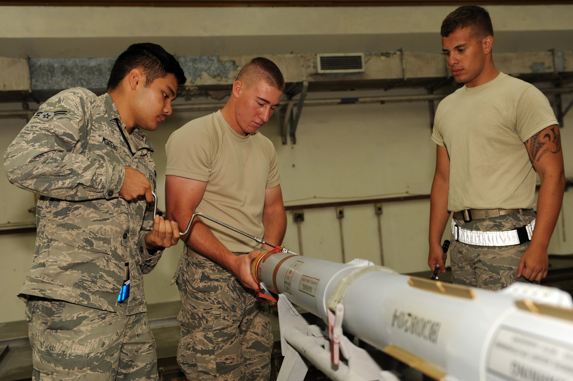 From left to right, U.S. Air Force Airmen 1st Class Miles Moreno and Troy Stephenson, 18th Munitions Squadron crew members, and Airman 1st Class Julian Vanegas, 18th MUNS crew chief, assemble a precision guided missile on Kadena Air Base, Japan, Sept. 4, 2014. PGMs are periodically taken apart when not in use to ensure the components are not damaged or expired. (U.S. Air Force photo by Airman 1st Class Zade C. Vadnais/Released)