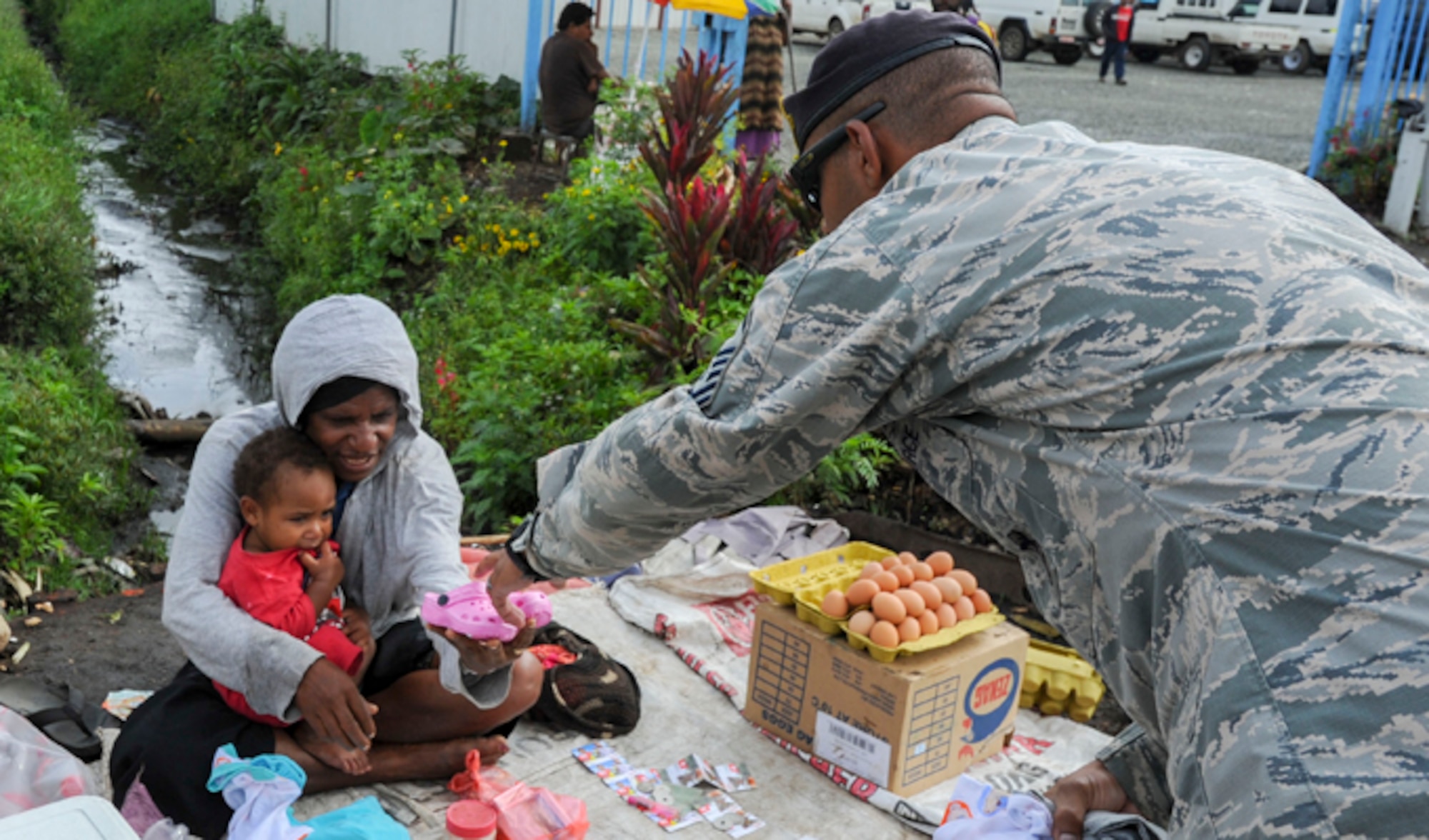 Master Sgt. Jamain Braxton hands a pair of shoes to a mother and her child Sept. 8, 2014, in the local community of Mount Hagen, Papua New Guinea. While deployed in support of Pacific Unity, Braxton organized a shoe drive to benefit children in the local community. Pacific Unity helps cultivate common bonds and foster goodwill between the U.S. and regional nations through multilateral humanitarian assistance and civil military operations. Braxton is the anti-terrorism officer for Pacific Unity 14-8 deployed from Andersen Air Force Base, Guam. (U.S. Air Force photo/Tech. Sgt. Terri Paden)                        