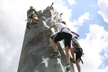 Marines with 2nd Marine Logistics Group, II Marine Expeditionary Force climb a rockwall during the barracks bash at Goettge Memorial Field aboard Marine Corps Base Camp Lejeune, N.C., Aug. 27, 2014. The overall goal of the barracks bash was to maintain unit cohesion and build camaraderie amongst Marines by competing in several sport events. (Marine Corps photo by Lance Cpl. Tyler Andersen)