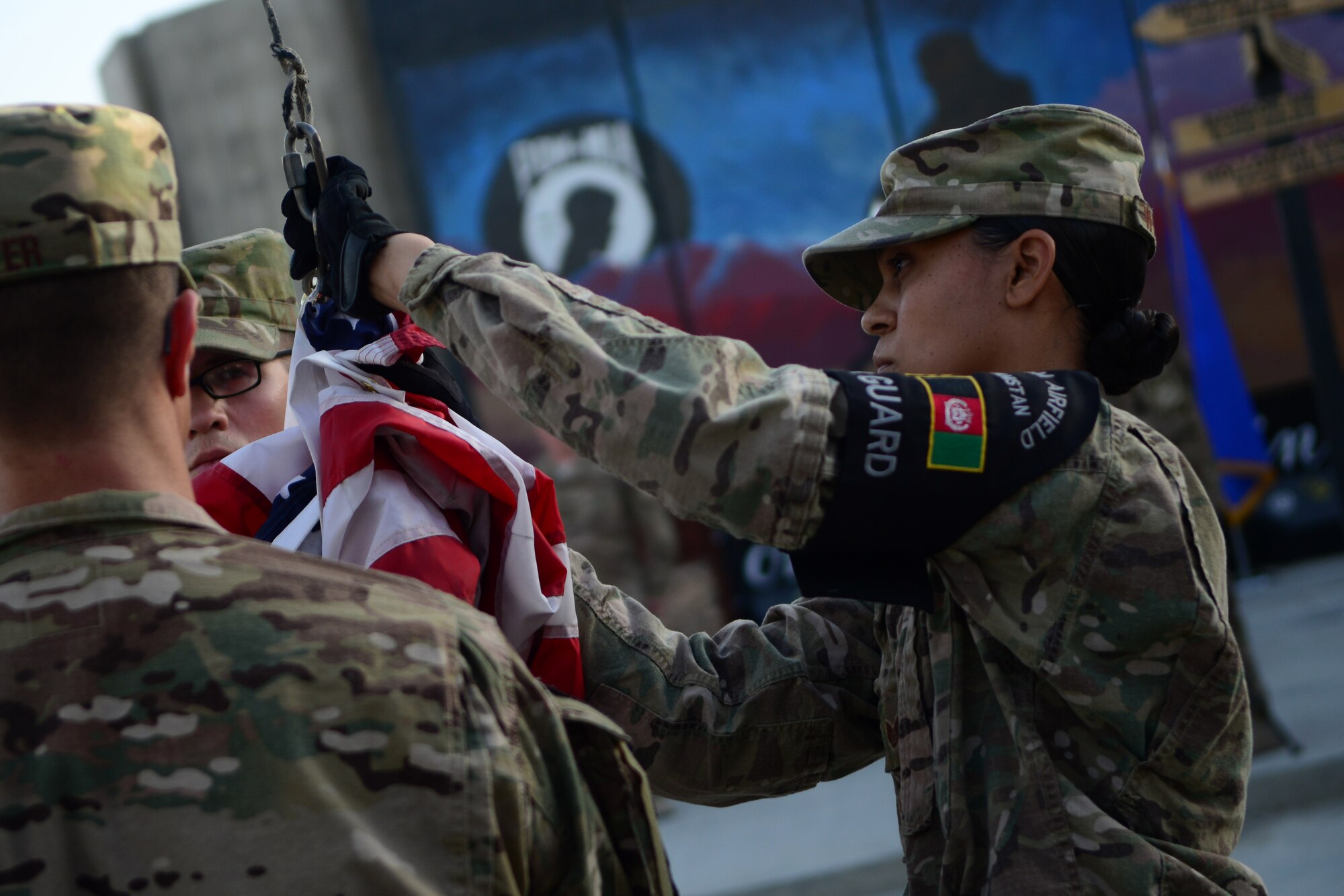U.S. Air Force Staff Sgt. Talisa Williams, 455th Expeditionary Force Support Squadron, lowers a U.S. flag during a retreat ceremony at Bagram Airfield, Afghanistan Sept. 11, 2014.  Airmen participated in a Patriot's Day Retreat and reenlistment ceremony Sept. 11, 2014.  Patriot's Day is an annual observance to remember those who were injured or died during the attacks on Sept. 11, 2001. (U.S. Air Force photo by Staff Sgt. Evelyn Chavez)