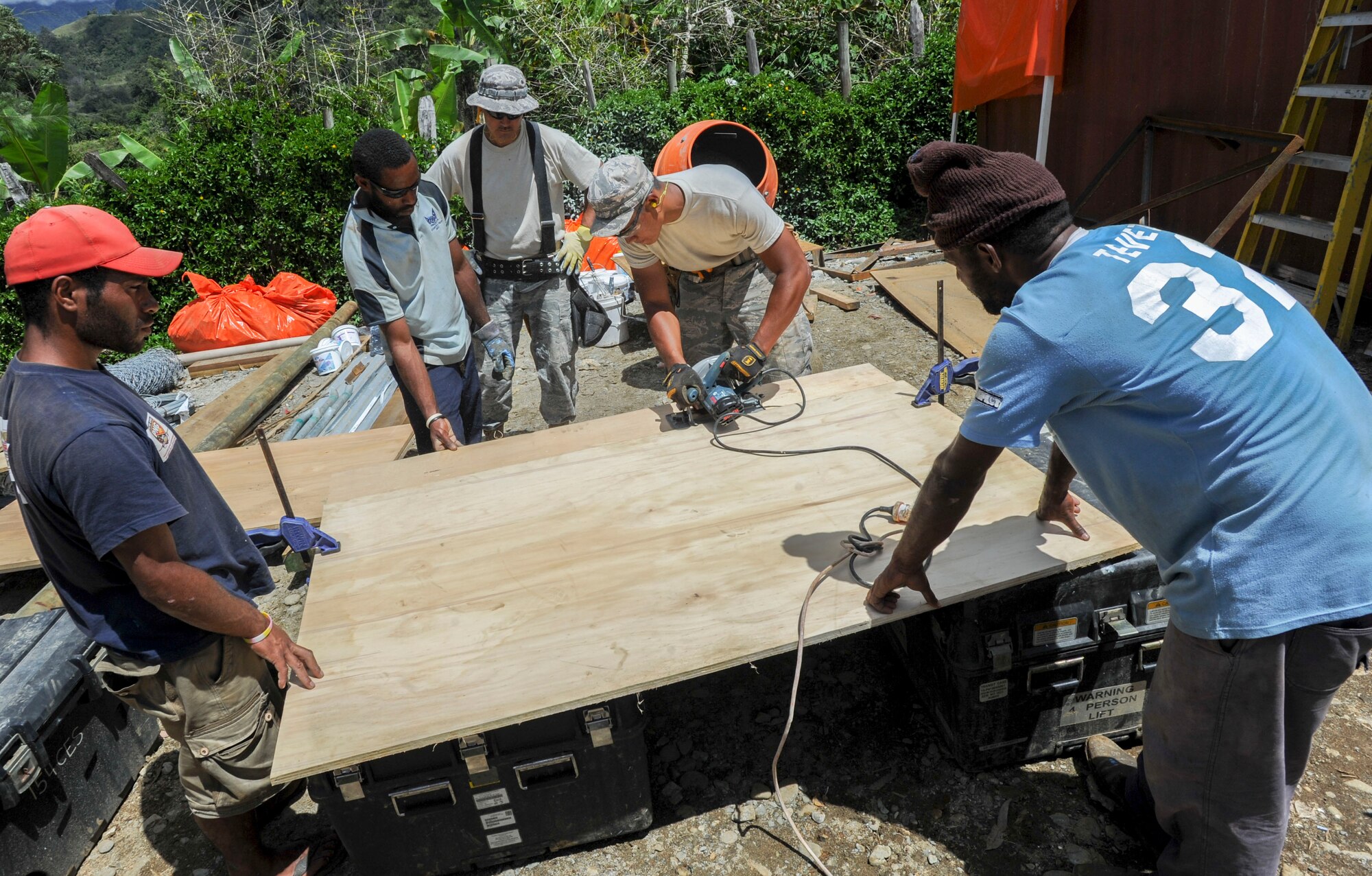 Members of the 154th Civil Engineer Squadron partner with day laborers from the local community to cut pieces of wood for a basketball backboard  Sept. 8, 2014, during Pacific Unity 14-8 in Mount Hagen, Papua New Guinea. Pacific Unity is a bilateral Engineering Civic Action Program conducted in the Asia-Pacific region in collaboration with host nation civil authorities and military service members that build upon previous engagements and exercises, and continue to mature U.S. and Asia-Pacific civil-military interoperability. The Airmen are deployed from the Hawaii Air National Guard. (U.S. Air Force photo/Tech. Sgt. Terri Paden)                           