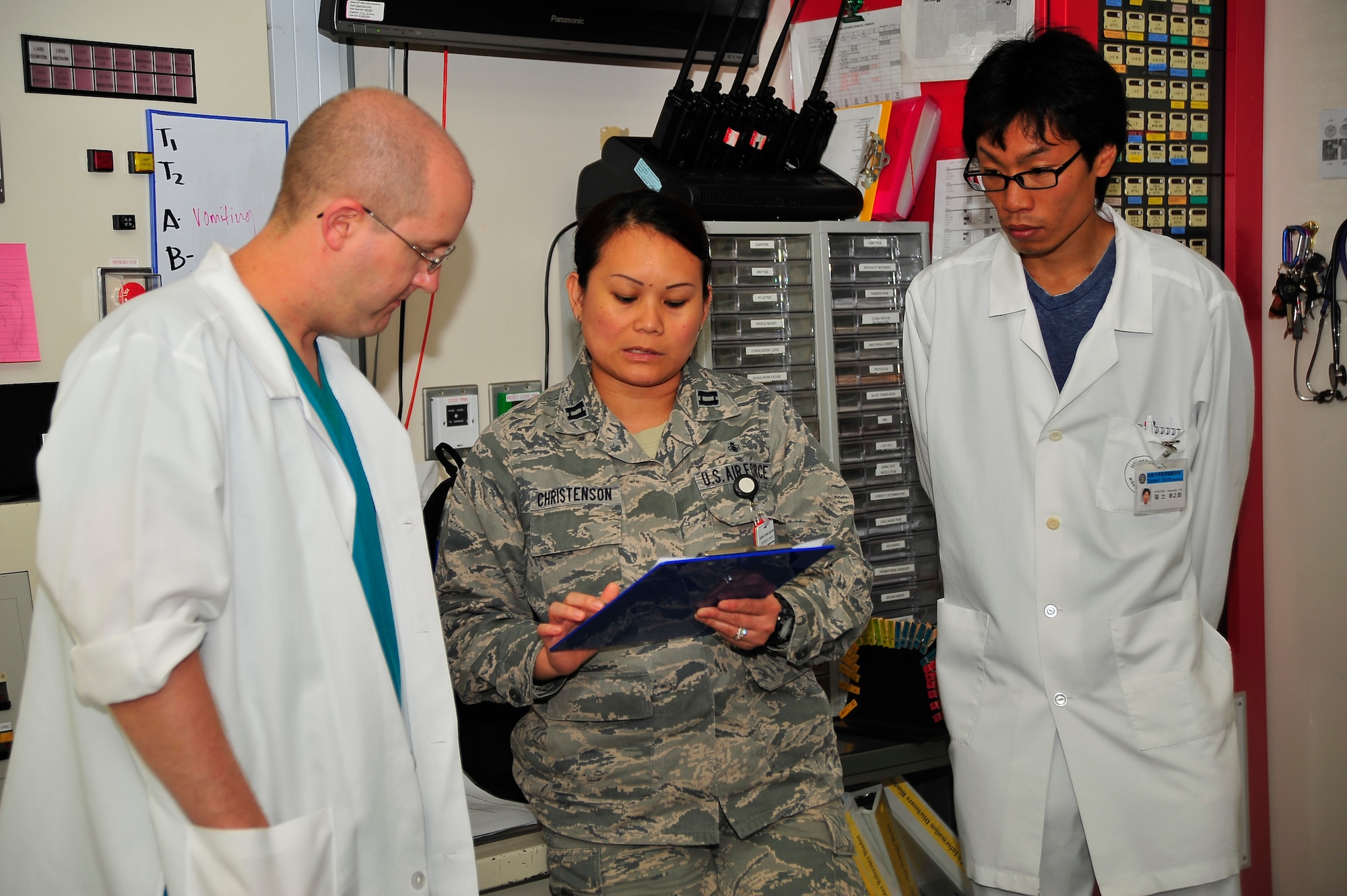U.S. Air Force Capt. Jimelyn Christenson, 35th Medical Operations Squadron clinical urgent care nurse, gives a report on the awaiting patient to Capt Kevan Long, 35 MDOS urgent care physician, and Japanese 3rd year medical student, Fukushi Konosuke from Hirosaki University at Misawa Air Base, Japan, August 28, 2014.  The 35th Medical Group hosted a shadowing program that allowed students from the Hirosaki University Medical School, Aomori Prefecture, to spend seven days observing American medical practices in action.  (U.S. Air Force photo/Tech. Sgt. April Quintanilla)