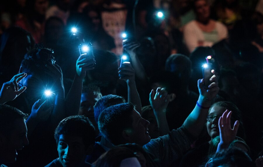 Audience members hold up cell phones with the flashlights turned-on during a performance by U.S. Air Force Band of the Golden West rock ensemble