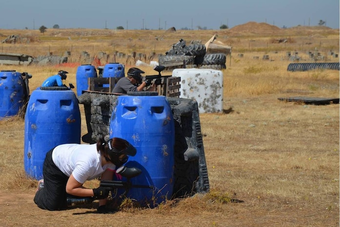 A member of the 9th Reconnaissance Wing ducks behind a barrier during paint-ball at Beale Air Force Base, Calif., Sept. 8, 2014.  This activity was part of a Comprehensive Airman Fitness day focused on building resiliency by strengthening relationships between co-workers. (Courtesy photo)