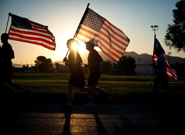 Members of Nellis Air Force Base run with the U.S. flag during the Old Glory Challenge at Nellis AFB, Nev., Sept. 11, 2014. During the Old Glory Challenge, participants were charged with continuously running with the U.S. flag in 30-minute increments from 6:30 a.m. to 4:30 p.m. The goal of the event was to help participants remember the events of 9/11, honor those lost in defending freedom and tell the story of all who serve in defense of freedom. (U.S. Air Force photo by Staff Sgt. Siuta B. Ika)