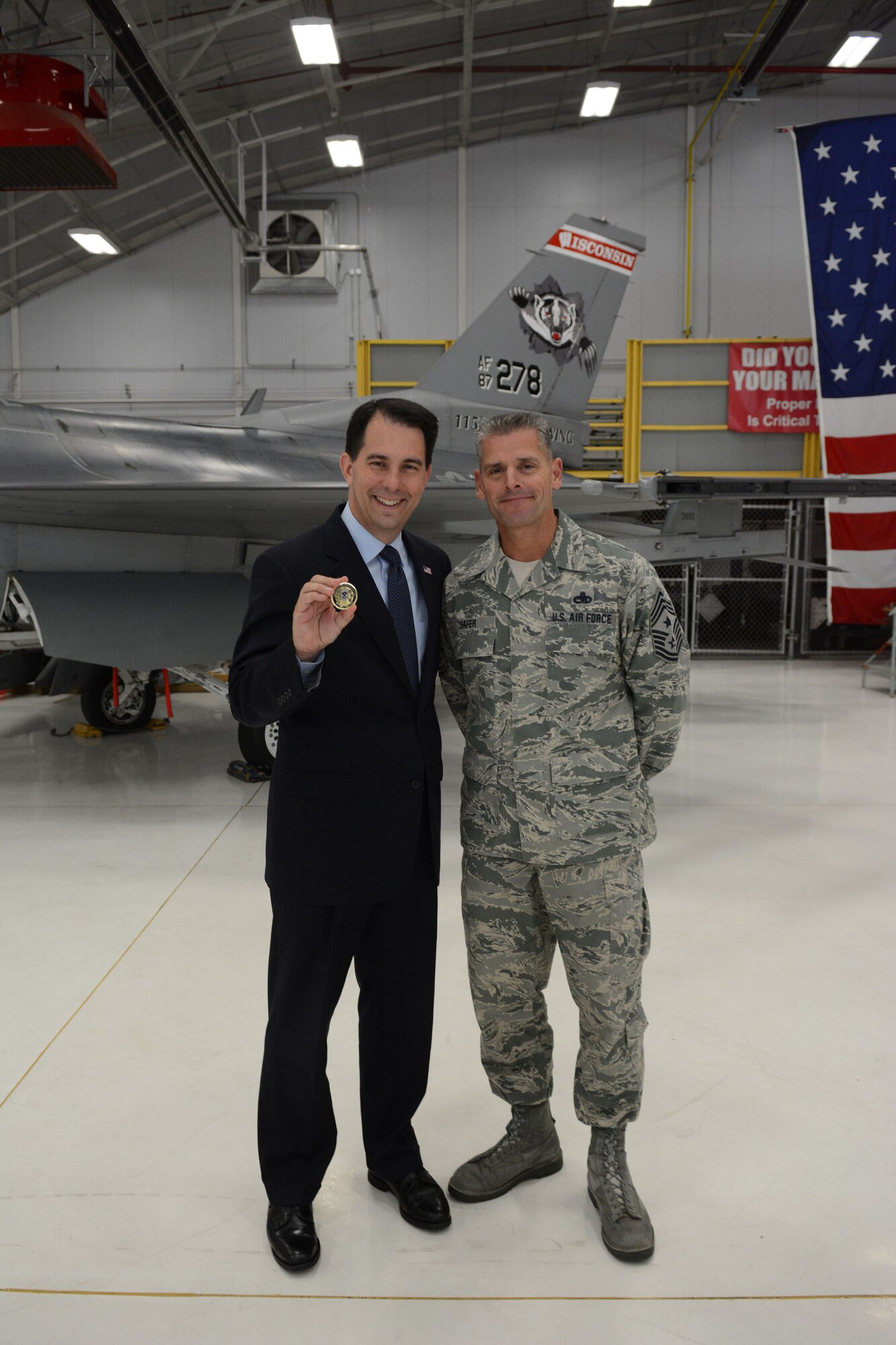 Governor Scott Walker, Wisconsin governor, shows off his new chief coin following a Sept. 11, 2001 remembrance ceremony in Hangar 406 at the 115th Fighter Wing in Madison, Wis., Sept. 11, 2014. Chief Master Sgt. Thomas Safer, 115 FW command chief, recently designed the new coin and chose Walker as the first recipient. (Air National Guard photo by Senior Airman Andrea F. Liechti)