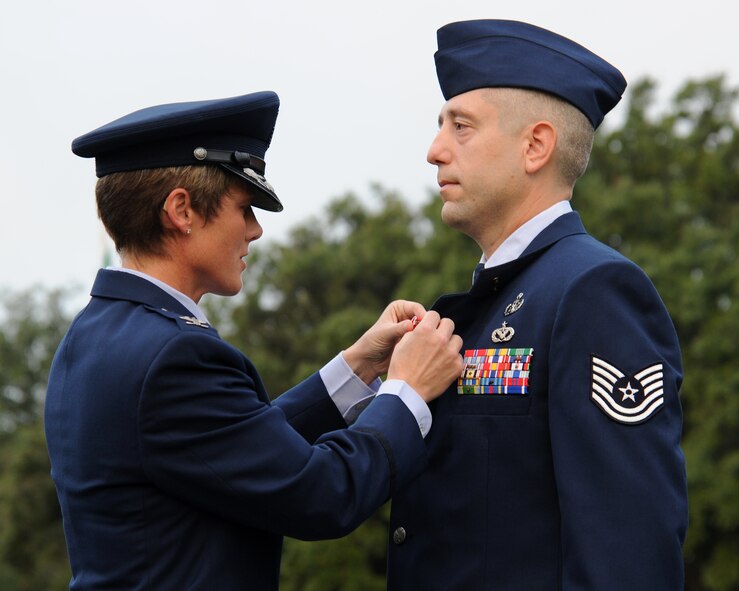 Col. Kristin Goodwin, 2nd Bomb Wing commander, presents Tech. Sgt. Joshua Flood, 2nd Civil Engineer Squadron Explosive Ordinance Disposal technician, the Bronze Star during the 9/11 Remembrance Ceremony on Barksdale Air Force Base, La., Sept. 11, 2014. Flood was recognized for guiding a three-member team to the safe and successful resolution of 34 combat missions while deployed in support of Operation Enduring Freedom. (U.S. Air Force photo/Senior Airman Jannelle Dickey)