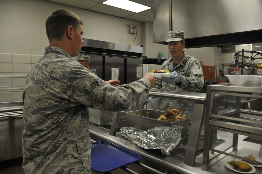 Col. Mark Anderson, 188th Wing commander, right, serves a "surf-n-turf" lunch meal to Airman 1st Class Parker Dunn at the Citizen Airman Dining Hall during a unit training assembly at Ebbing Air National Guard Base, Fort Smith, Arkansas on Sept. 7, 2014. (U.S. Air National Guard photo by Staff Sgt. John Suleski/released)