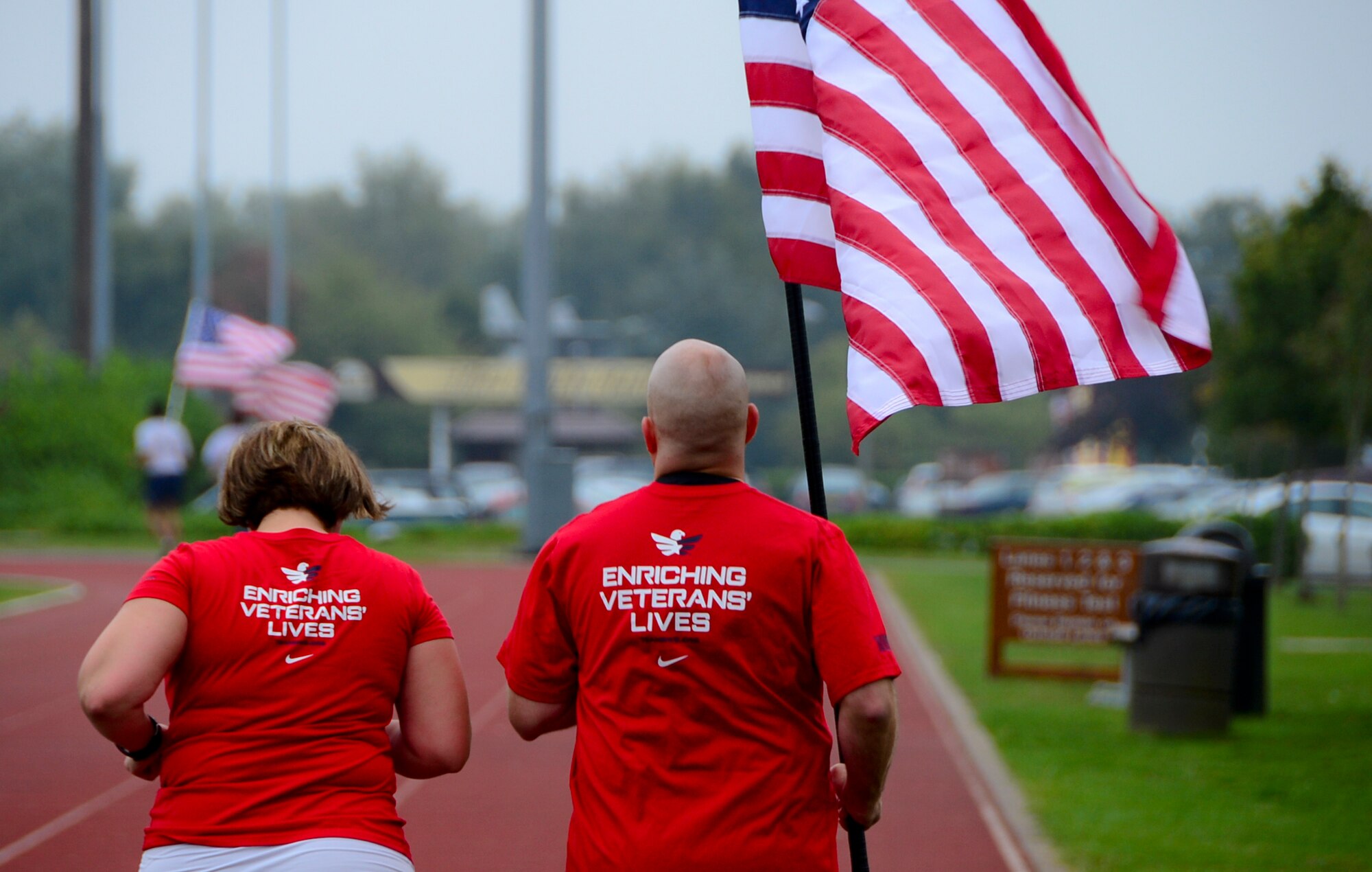 Tech. Sgt. Jennifer Aucoin, 48th Maintenance Group training manager, runs with her husband Master Sgt. Jason Aucoin, 48th Fighter Wing ground safety office manager, during a 9/11 Memorial 5K Run/Walk “Moving Tribute” at Royal Air Force Lakenheath, England, Sept. 11, 2014. Their ‘Team Red, White and Blue’ shirts, represents the partnership between civilians and veterans whose mission is to strengthen and enhance the lives of veterans by connecting them with their local community through various social and physical activities. (U.S. Air Force photo by Airman 1st Class Erin O’Shea/Released)