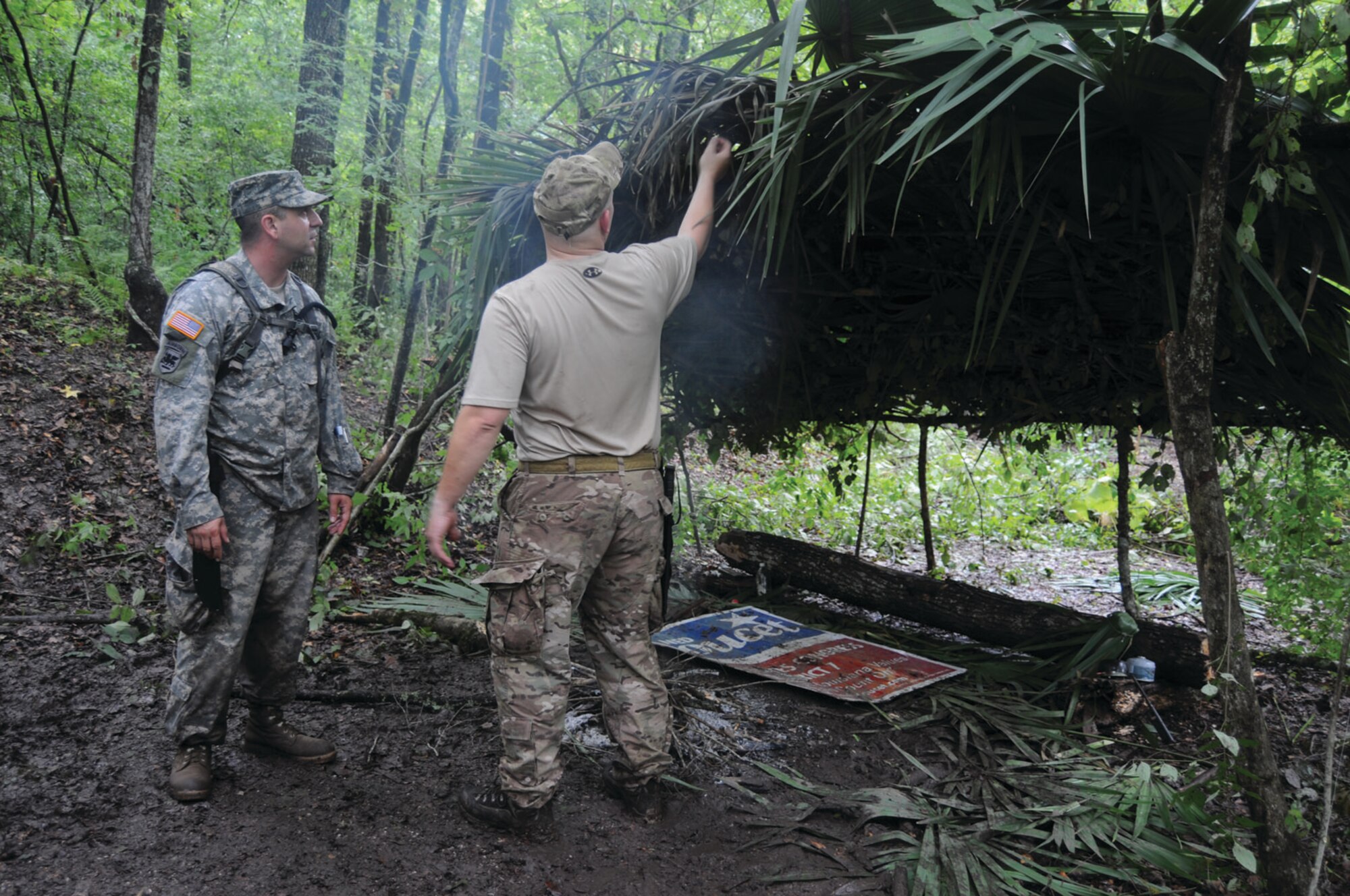 A student explains to medic Sgt. 1st Class Remo Soldaini, 1st Bn (Abn), 509th Inf Reg, how he and his team wove palm fronds and other natural materials into a rainproof shelter during a survival exercise held Aug. 30-Sept. 1 in the Atchafalaya Basin. (U.S. Army photo by Jean Dubiel)