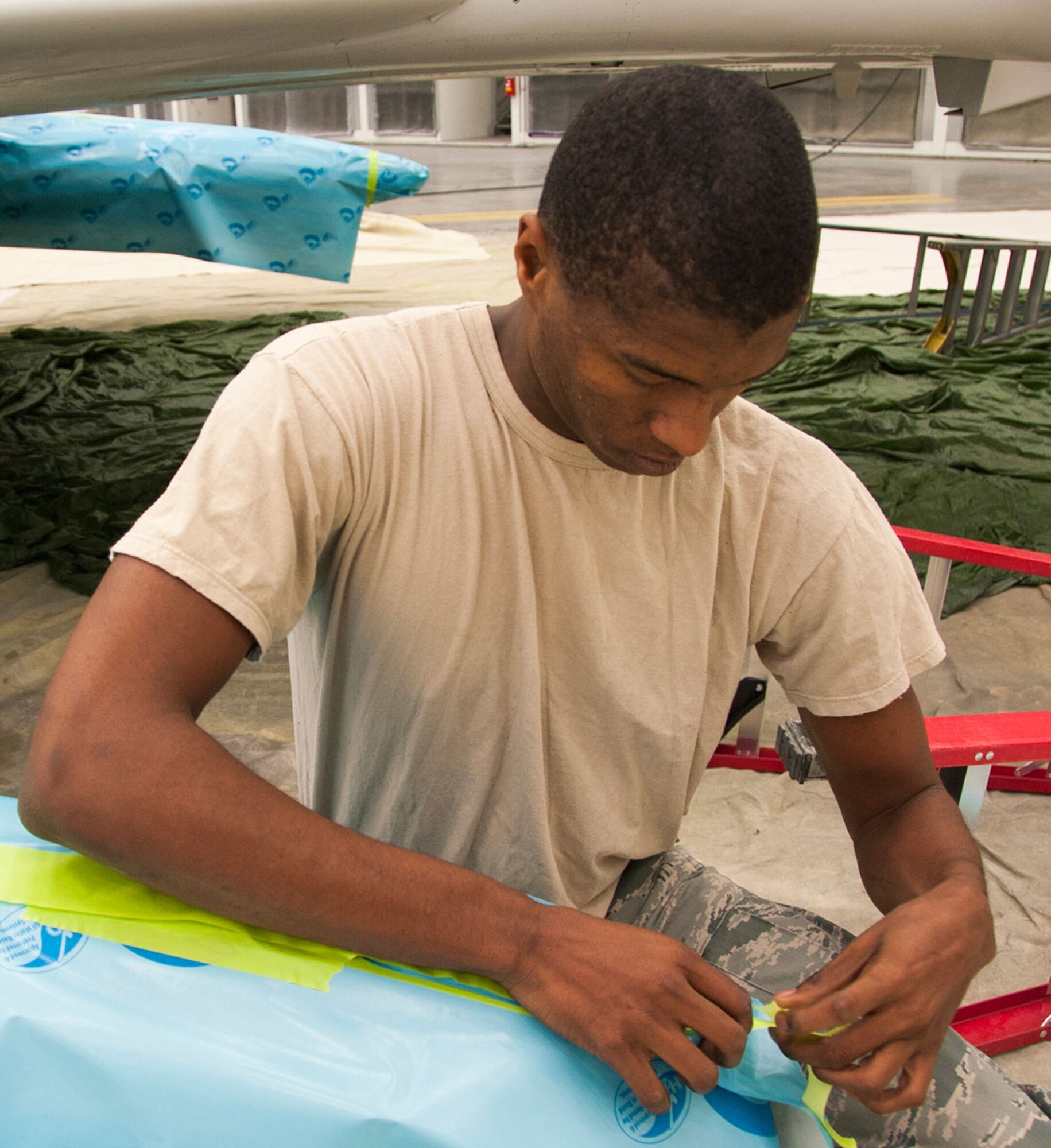 Airman 1st Class Kristian Brown, 3rd Aircraft Maintenance Squadron aircraft maintenance apprentice, masks off a section of an F-4 Phantom II for a routine paint job on Joint Base Elmendorf-Richardson, Alaska, Sept. 9, 2014. Brown masks certain spots of the F-4 to ensure those areas are not painted with a certain color scheme. There are eight different colors painted on the F-4 during refurbishing. (U.S. Air Force photo/Airman 1st Class Tammie Ramsouer)