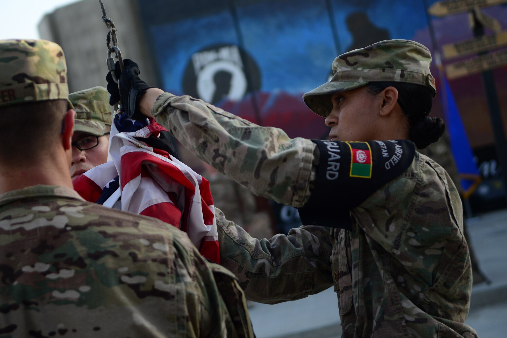 U.S. Air Force Staff Sgt. Talisa Williams, 455th Expeditionary Force Support Squadron, lowers a U.S. flag during a retreat ceremony at Bagram Airfield, Afghanistan Sept. 11, 2014.  Airmen participated in a Patriot's Day Retreat and reenlistment ceremony Sept. 11, 2014.  Patriot  Day is an annual observance to remember those who were injured or died during the attacks on Sept. 11, 2001. (U.S. Air Force photo by Staff Sgt. Evelyn Chavez/Released)