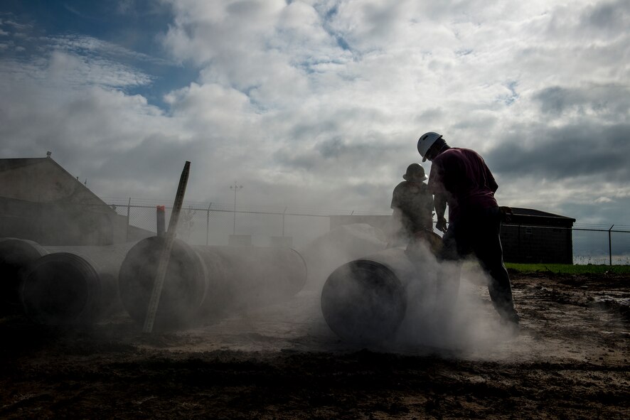 Construction workers cut a segment of drainage pipe Sept. 9, 2014, at Moody Air Force Base, Ga. Road construction is scheduled to be completed in three phases to minimize travel impact via road closures and single lanes of traffic. (U.S. Air Force photo by Airman 1st Class Ryan Callaghan/Released)