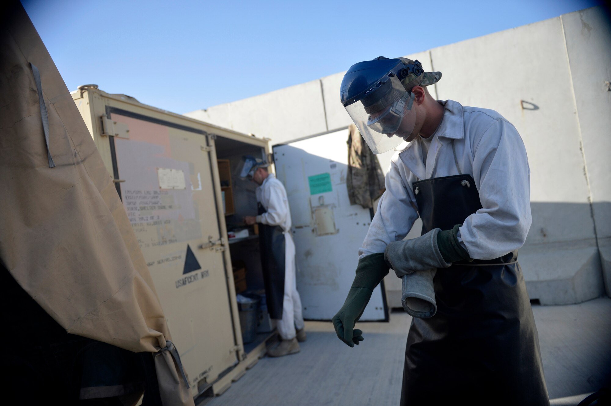 U.S. Air Force Staff Sgt. Taj Copeland, 455th Expeditionary Logistics Readiness Squadron fuels distribution supervisor, dons protective gear before  refilling liquid oxygen carts at Bagram Airfield, Afghanistan Aug. 5, 2014. The cryogenics technicians support 6,000 aircraft missions and provide more than 4,000 gallons of liquid oxygen per month. Copeland is deployed from Nellis Air Force Base, Nev. and a native of Tampa, Fla. (U.S. Air Force photo by Staff Sgt. Evelyn Chavez/Released)