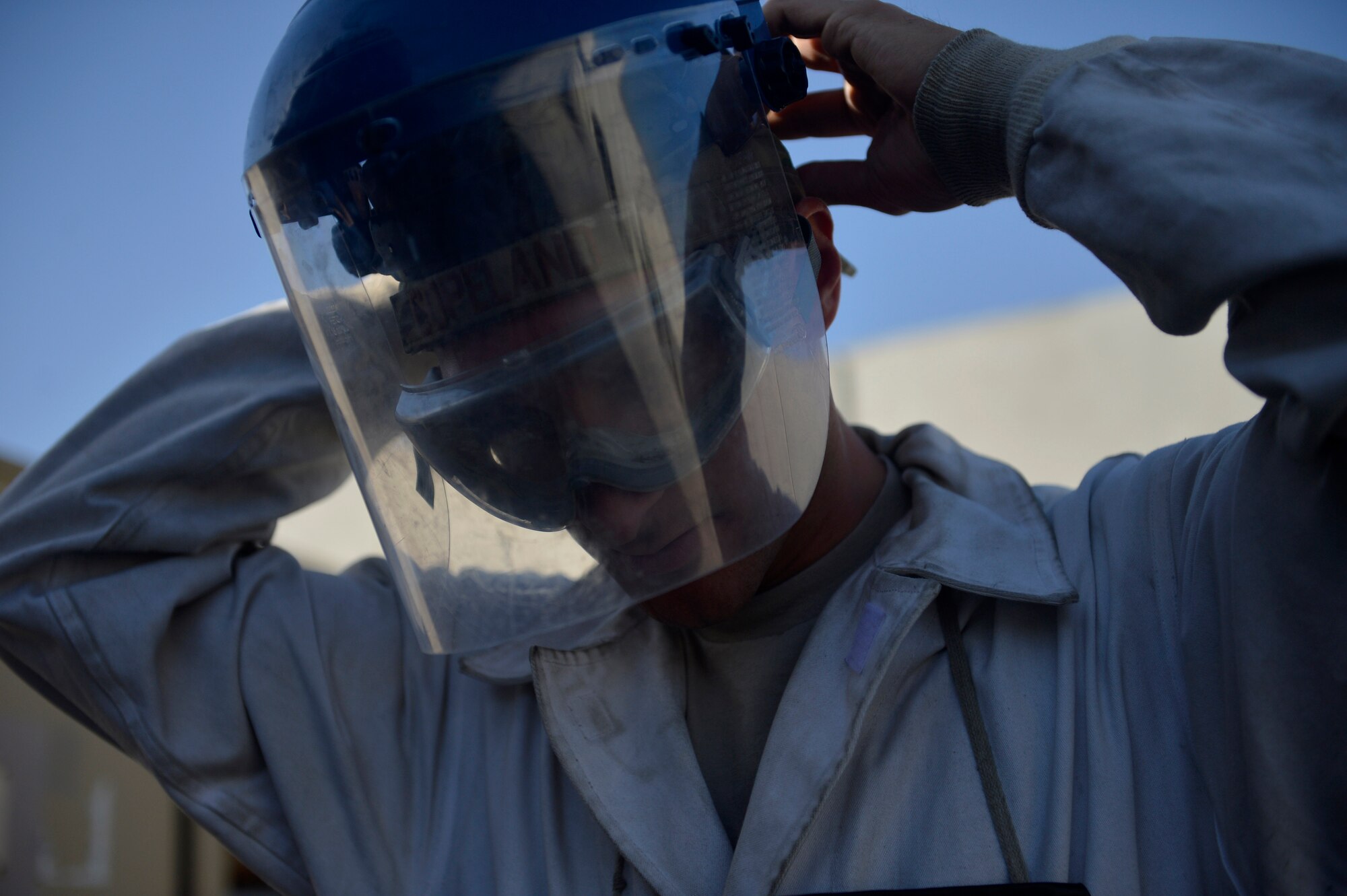 U.S. Air Force Staff Sgt. Taj Copeland, 455th Expeditionary Logistics Readiness Squadron  fuels distribution supervisor, adjusts his face shield before  refilling liquid oxygen carts at Bagram Airfield, Afghanistan Aug. 5, 2014. The cryogenics flight is responsible for providing more than 4,000 gallons of liquid oxygen per month to aircraft.  Copeland is deployed from Nellis Air Force Base, Nev. and a native of Tampa, Fla. (U.S. Air Force photo by Staff Sgt. Evelyn Chavez/Released)