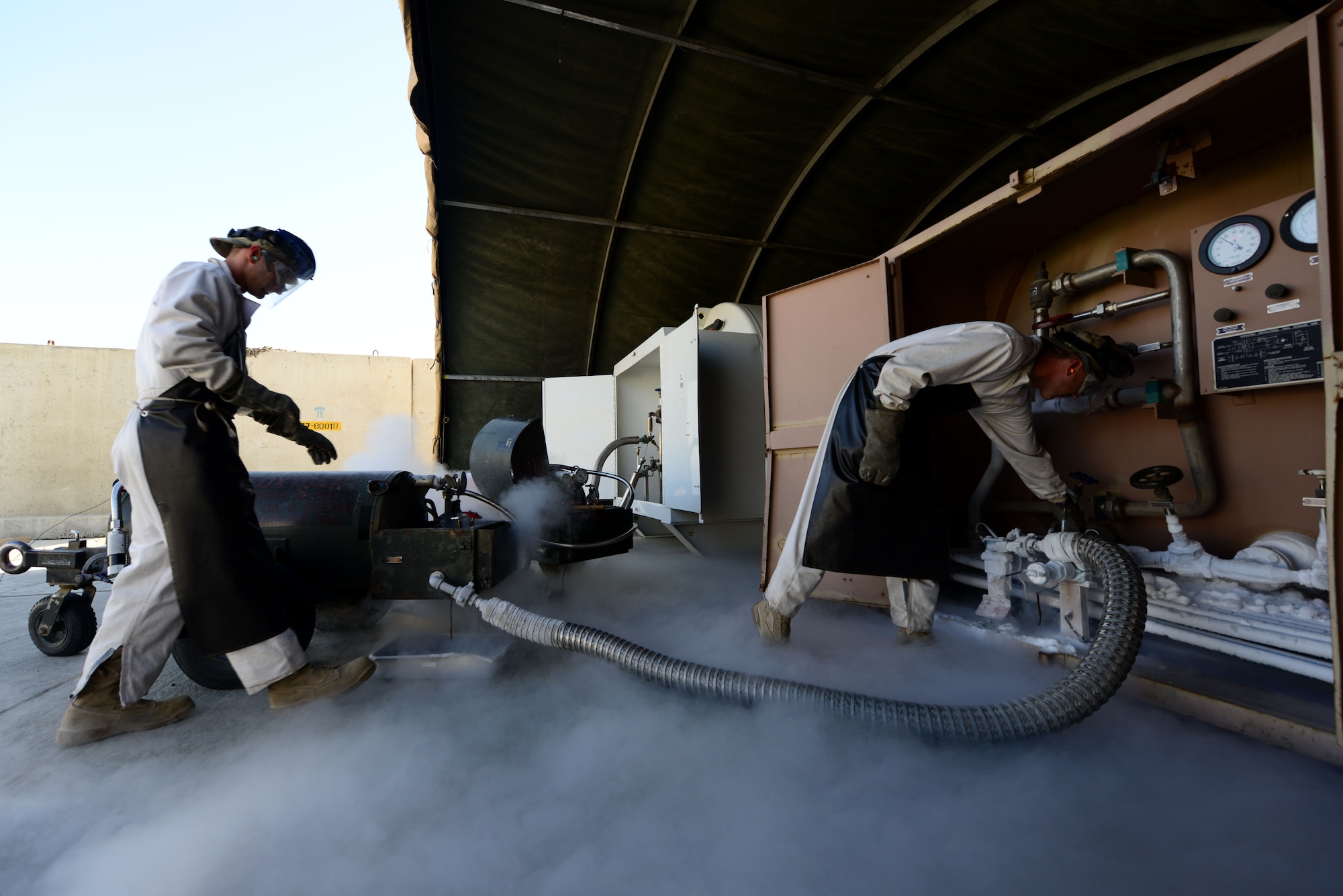 (From left) U.S. Air Force Staff Sgt. Taj Copeland, 455th Expeditionary Logistics Readiness squadron, and Staff Sgt. James Brumbaugh, 455 ELRS fuels cryogenics non-commisioned officer in-charge, refill liquid oxygen carts or LOX for aircraft at Bagram Airfield, Afghanistan Sept. 4, 2014.  The cryogenics flight is responsible for providing more than 4,000 gallons of liquid oxygen per month to aircraft.  Brumbaugh is deployed from Davis-Monthan Air Force Base, Ariz. and a native of Clarkrange, Tenn.  Copeland is deployed from Nellis Air Force Base, Nev. and a native of Tampa, Fla. (U.S. Air Force photo by Staff Sgt. Evelyn Chavez/Released)