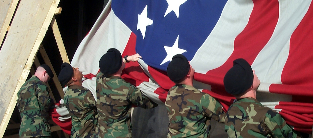 Soldiers from A Company, 3rd Infantry – “The Old Guard” -- gather the giant garrison flag being lowered from the side of the Pentagon, where it had hung beside the impact site of the 9/11 terrorist attack, Oct. 11, 2001. The flag was ceremonially retired. DoD photo by Jim Garamone