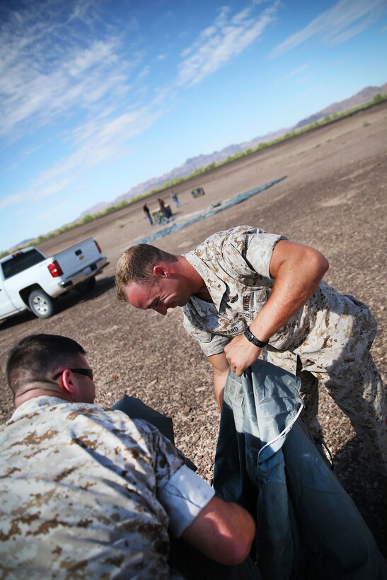 1st Lt. Stephen Shepard, Landing Support Company, Air Delivery platoon commander, packs away a Joint Precision Airdrop System parachute during testing of the system Aug. 26, 2014, at Yuma Proving Ground, Ariz. The JPADS systems use GPS, a modular autonomous guidance unit, or MAGU, a parachute and electric motors to guide cargo within 150 meters of their target points. To test its precision, the Marines used a series of palletized loads attached to parachutes with the GPS integrated system and dropped them from various heights.  (U.S. Marine Corps photo by Sgt. Laura Gauna/ released)