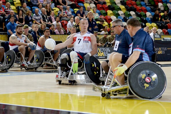Army Sgt. Ryan McIntosh, representing the U.S., passes the ball around two defenders during  a wheelchair rugby match against Australia Sept. 12, 2014, at the 2014 Invictus Games in London. The U.S. won the match 14-4. Invictus Games is an international competition that brings together wounded, injured and ill service members in the spirit of friendly athletic competition. American Soldiers, Sailors, Airmen and Marines are representing the U.S. in the competition which is taking place Sept. 10-14. (U.S. Navy photo/Mass Communication Specialist 2nd Class Joshua D. Sheppard)