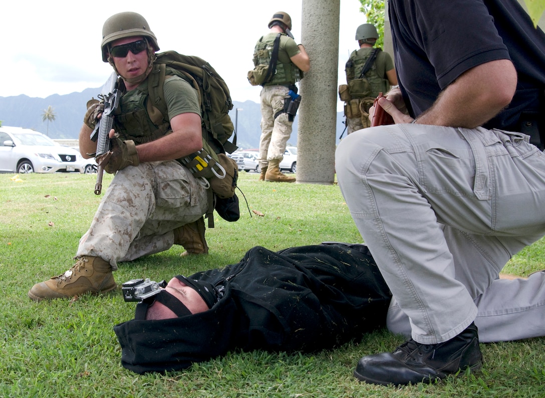 MARINE CORPS BASE HAWAII - Cpl. Joseph Schlagel (left), a Marine with the Provost Marshal’s Office Special Reaction Team provides security in front of Naval Health Clinic Hawaii Kaneohe Bay branch during Lethal Breeze 2014, Sept. 9, 2014. Petty Officer 2nd Class David Shepardson, a hospital corpsman with NHCH playing a subdued active shooter, lies on the grass. (U.S. Marine Corps photo by Kristen Wong)