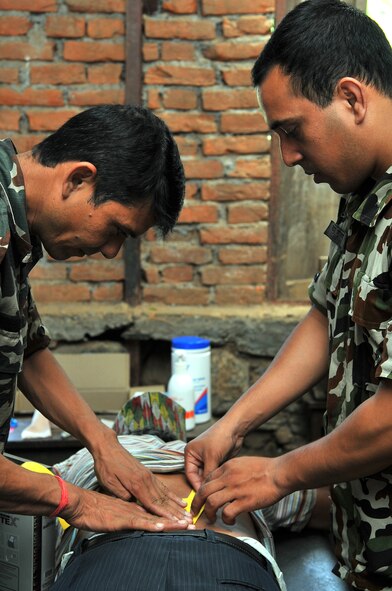 Nepalese Army Tech. Sgt. Chanda Silwal (left), physical therapy assistant, and Capt. (Dr.) Madan Goutam (right), physical therapist, apply kinesio tape to a patient at a health services outreach site in Shaktikhor, Nepal, Sept. 12, 2014, as part of Operation Pacific Angel-Nepal. PACANGEL helps cultivate common bonds and foster goodwill between the U.S., Nepal and regional nations by conducting multilateral humanitarian assistance and civil military operations. (U.S. Air Force photo by Staff Sgt. Melissa B. White/Released)