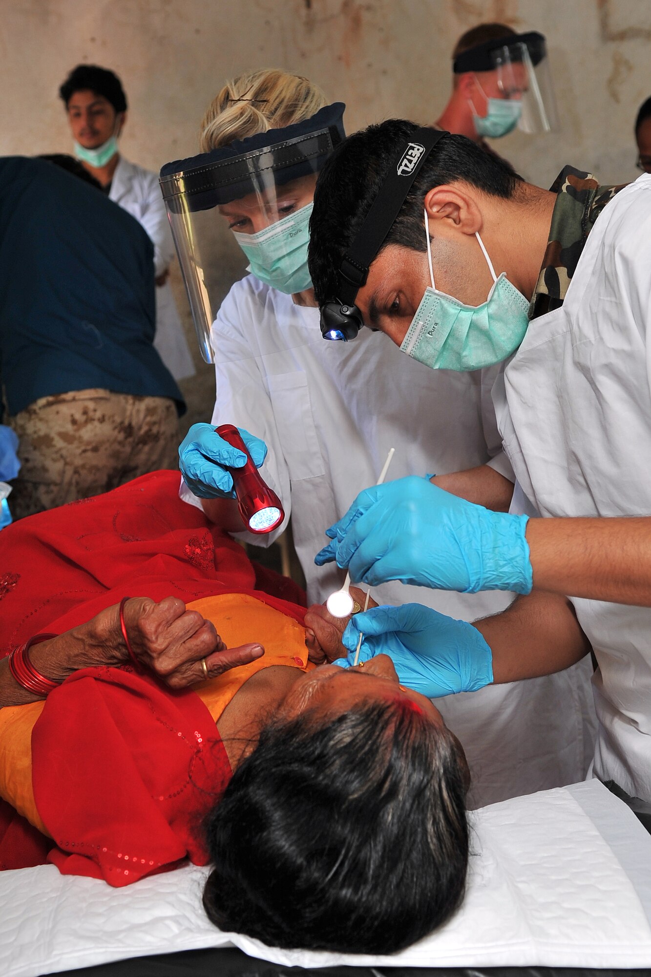 Nepalese Army Sgt. Santosh Panta, dentist, and Royal Australian Air Force Sgt. Kerry Sears, Operation Pacific Angel-Nepal dental assistant, examine a patient at a health services outreach location in Shaktikhor, Nepal, Sept. 12, 2014. PACANGEL helps cultivate common bonds and foster goodwill between the U.S., Nepal and regional nations by conducting multilateral humanitarian assistance and civil military operations. (U.S. Air Force photo by Staff Sgt. Melissa B. White/Released)